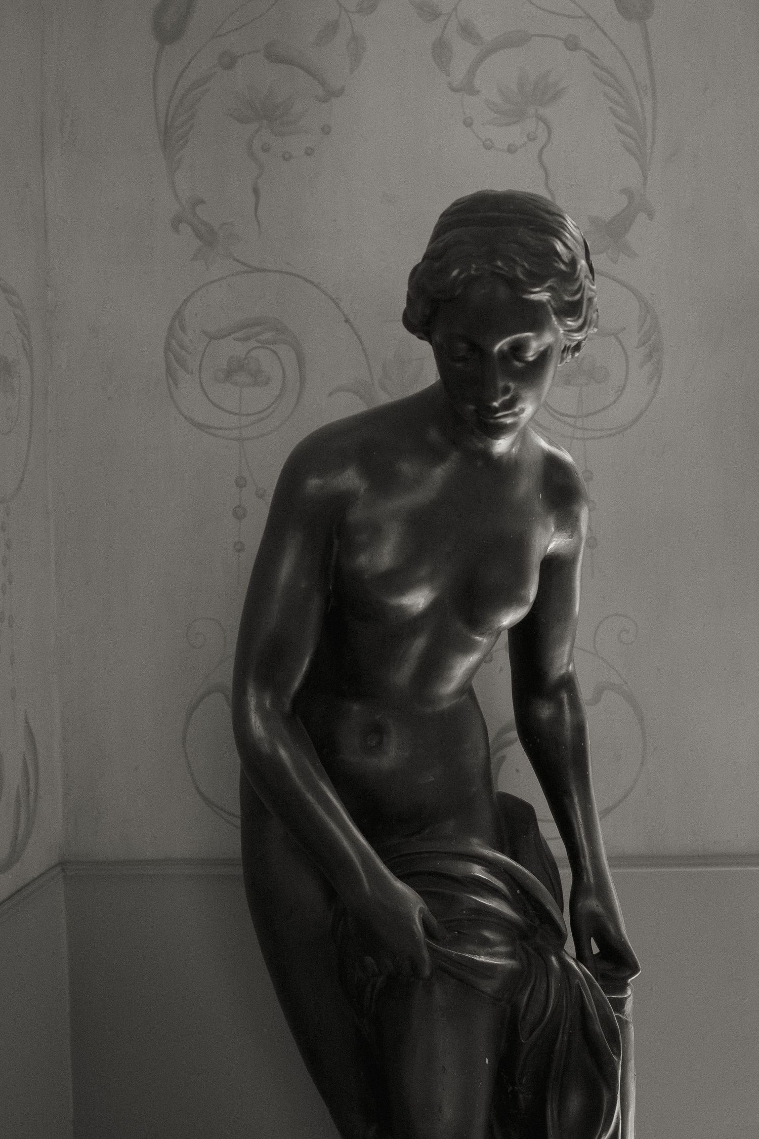 A series of four black and white photographs showing a bronze sculpture from different angles against a light background.