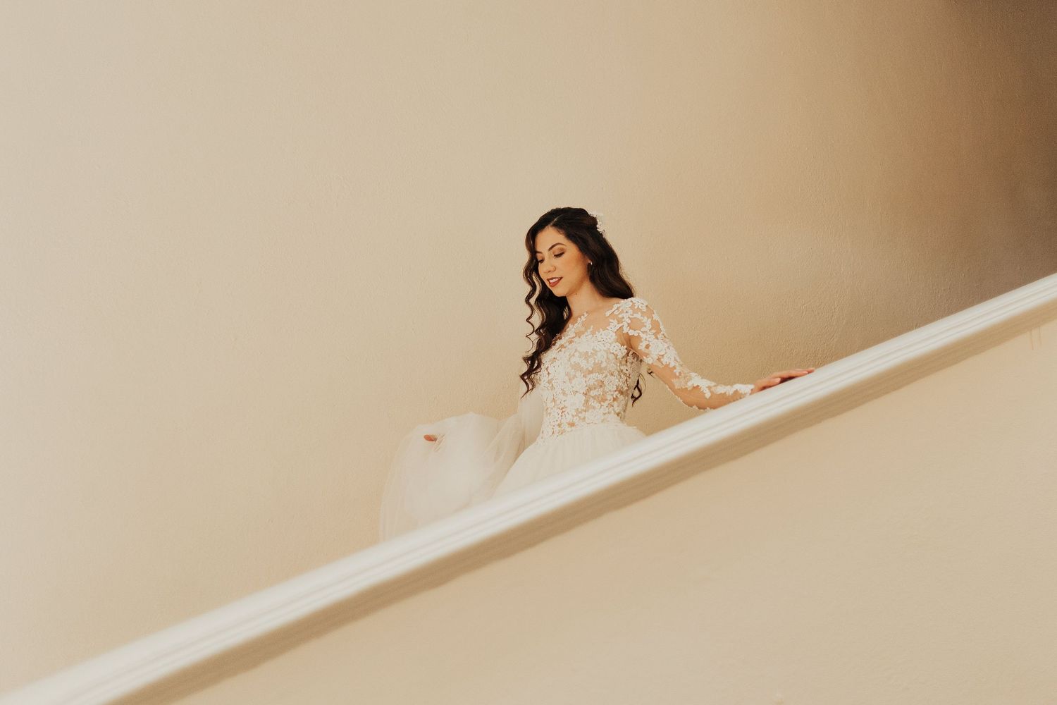 Romantic bridal portraits taken against a neutral beige wall with soft lighting.