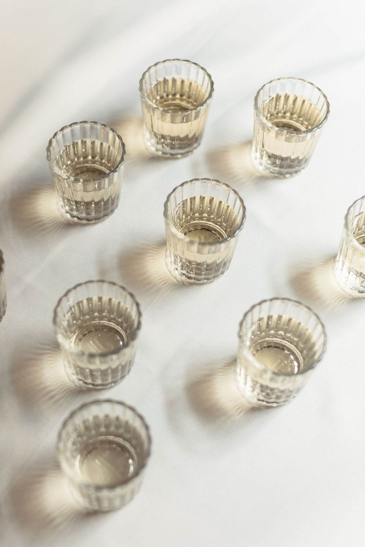 Small glass bowls with ribbed edges arranged in a repeating pattern against a white background.