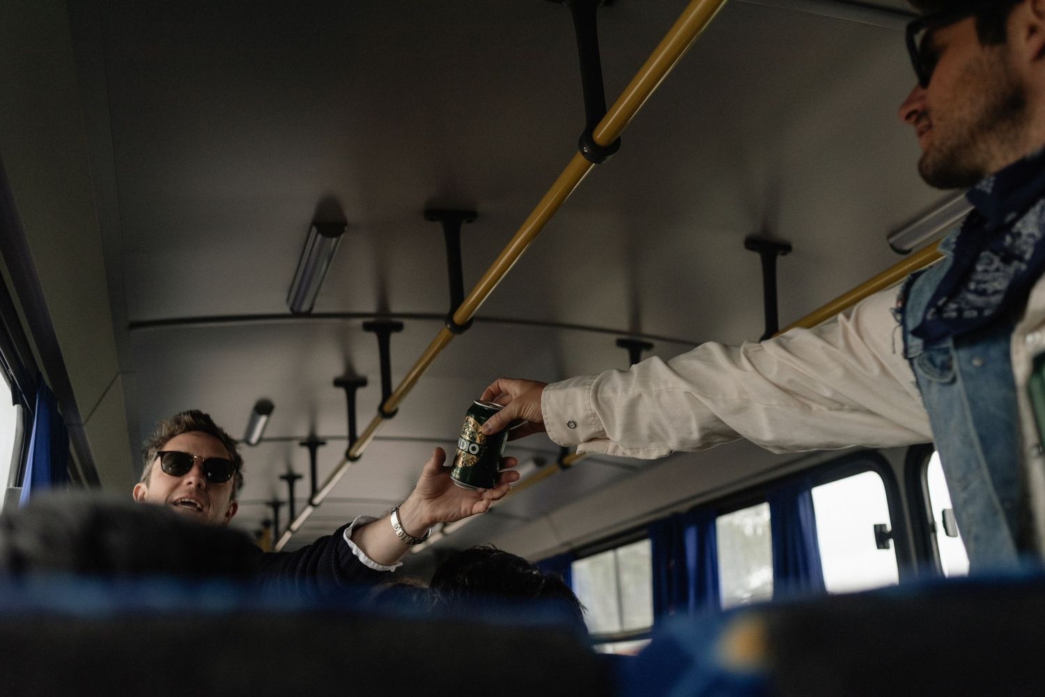 Passengers sitting casually on public transportation with one person leaning back and stretching across bus seats.