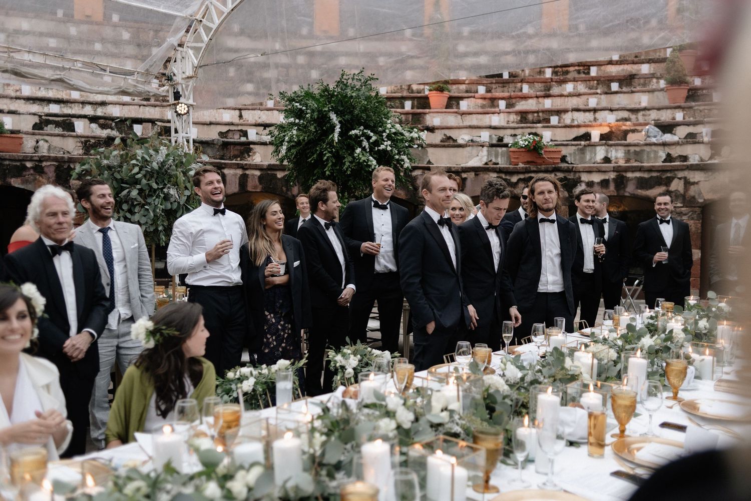 Elegantly decorated reception dining table with white flowers and candles in a rustic stone venue.