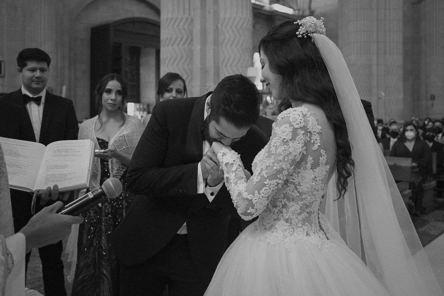 Black and white photo of a traditional wedding ceremony in an elegant church setting.