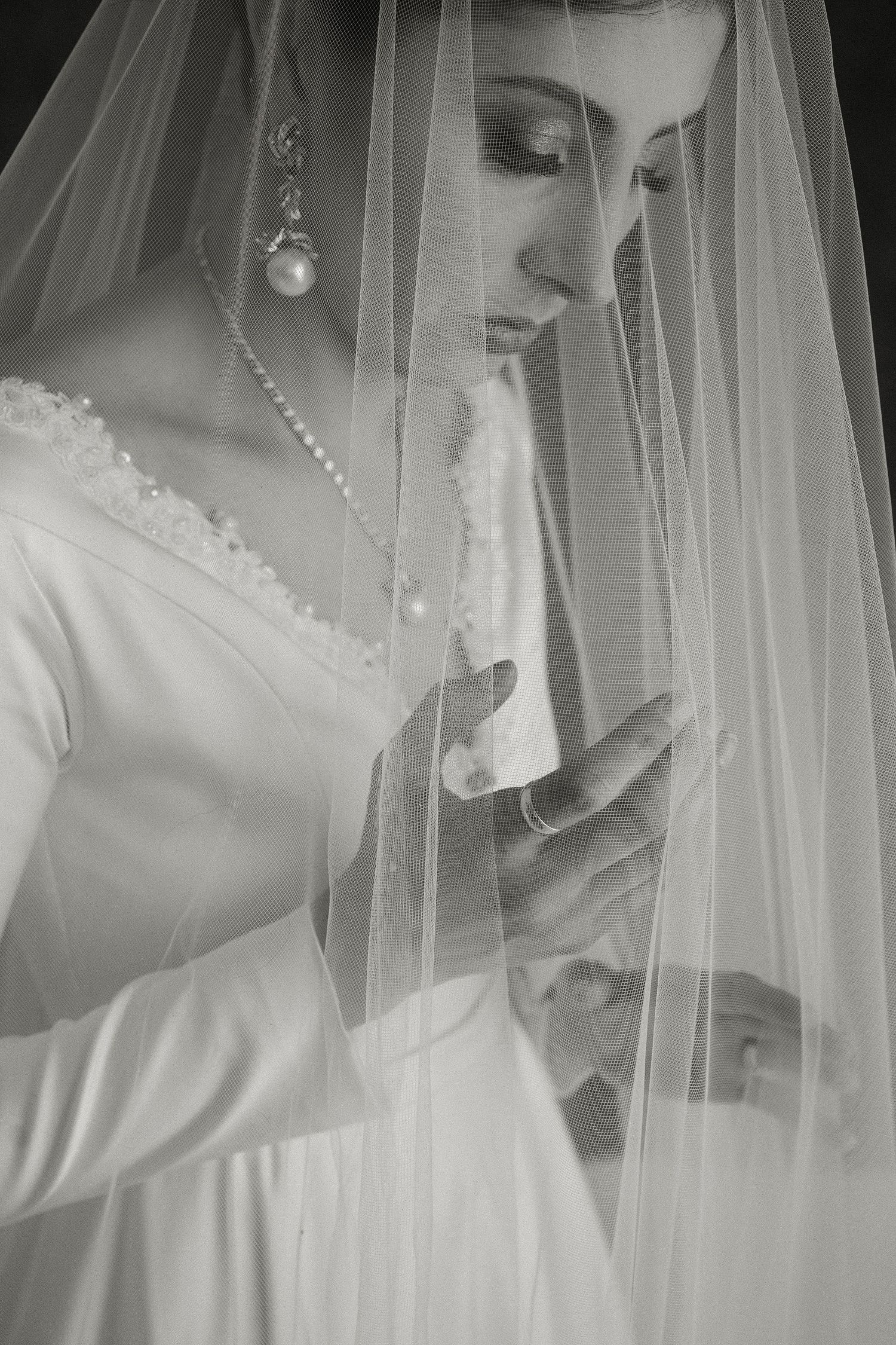 Ethereal black and white bridal portrait showing delicate veil and pearl details.