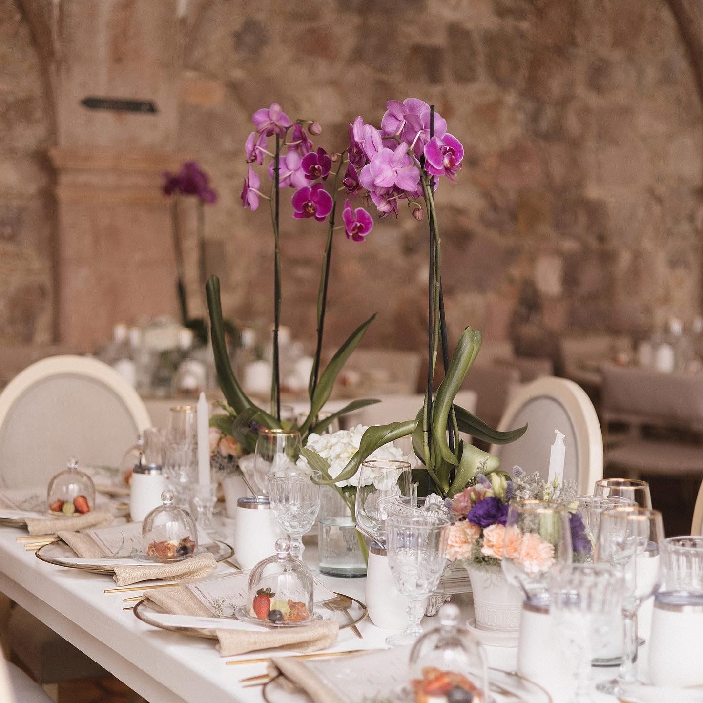 Elegant table setting with pink orchids and crystal glassware at a formal event.