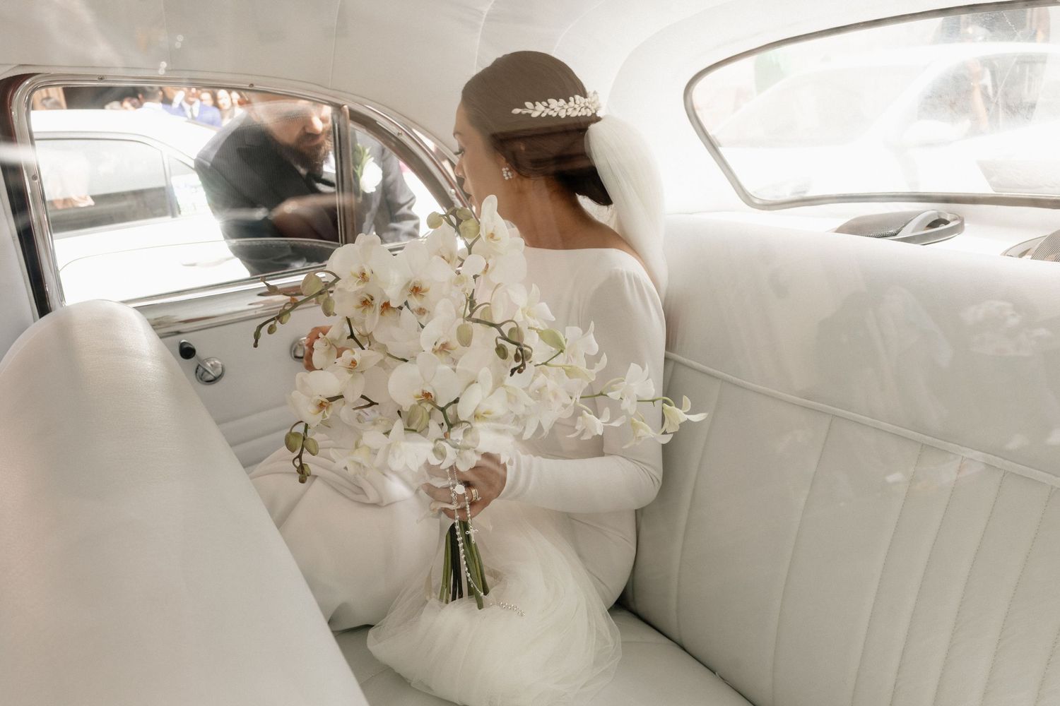 A luxurious white leather interior of a car with decorative floral arrangements visible in the back seat.