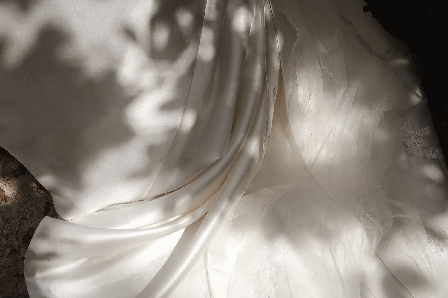 Ethereal close-up of flowing white wedding dress fabric with dramatic shadow play.