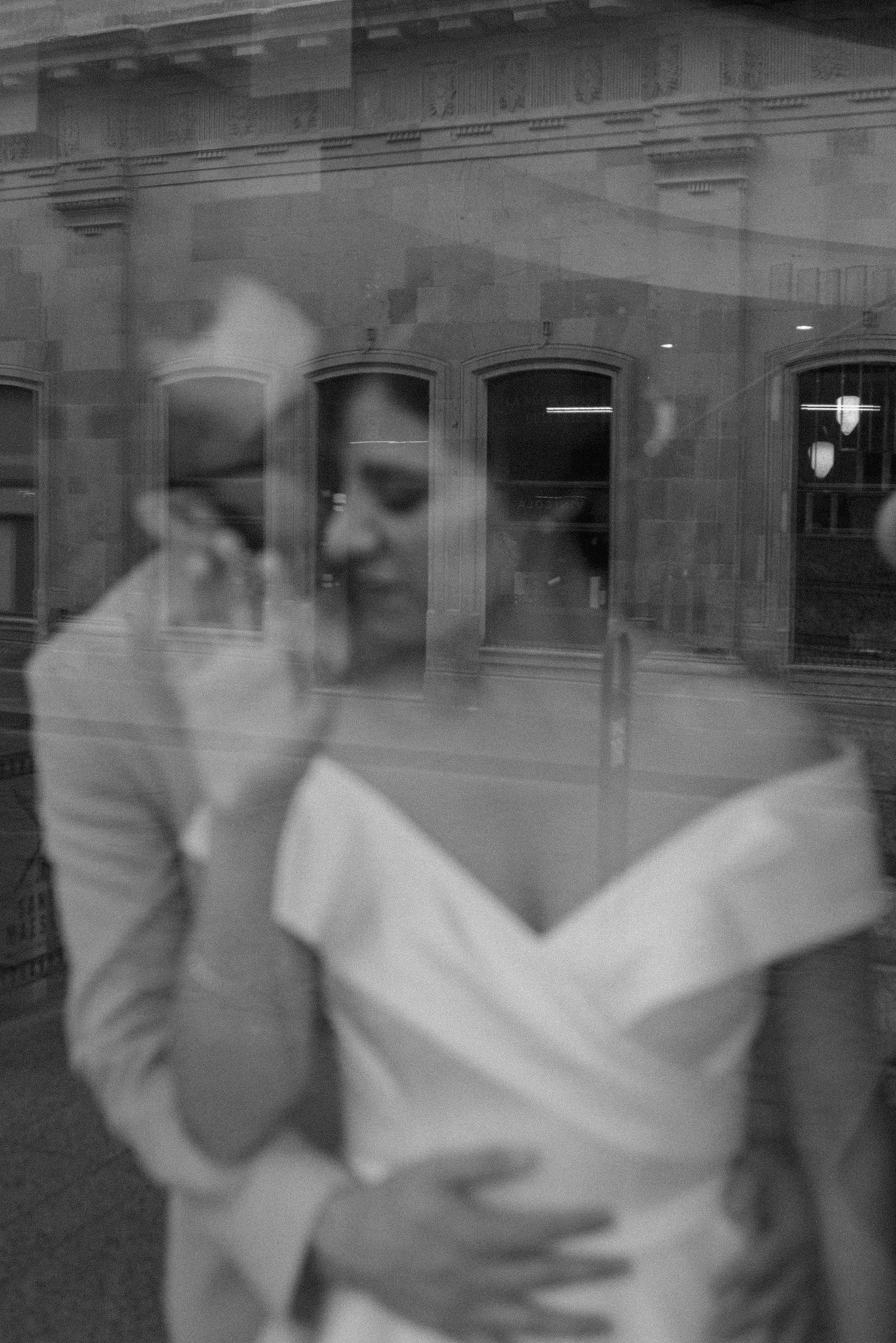 Artistic black and white reflection of a bride in a window, creating a dreamy double exposure effect.