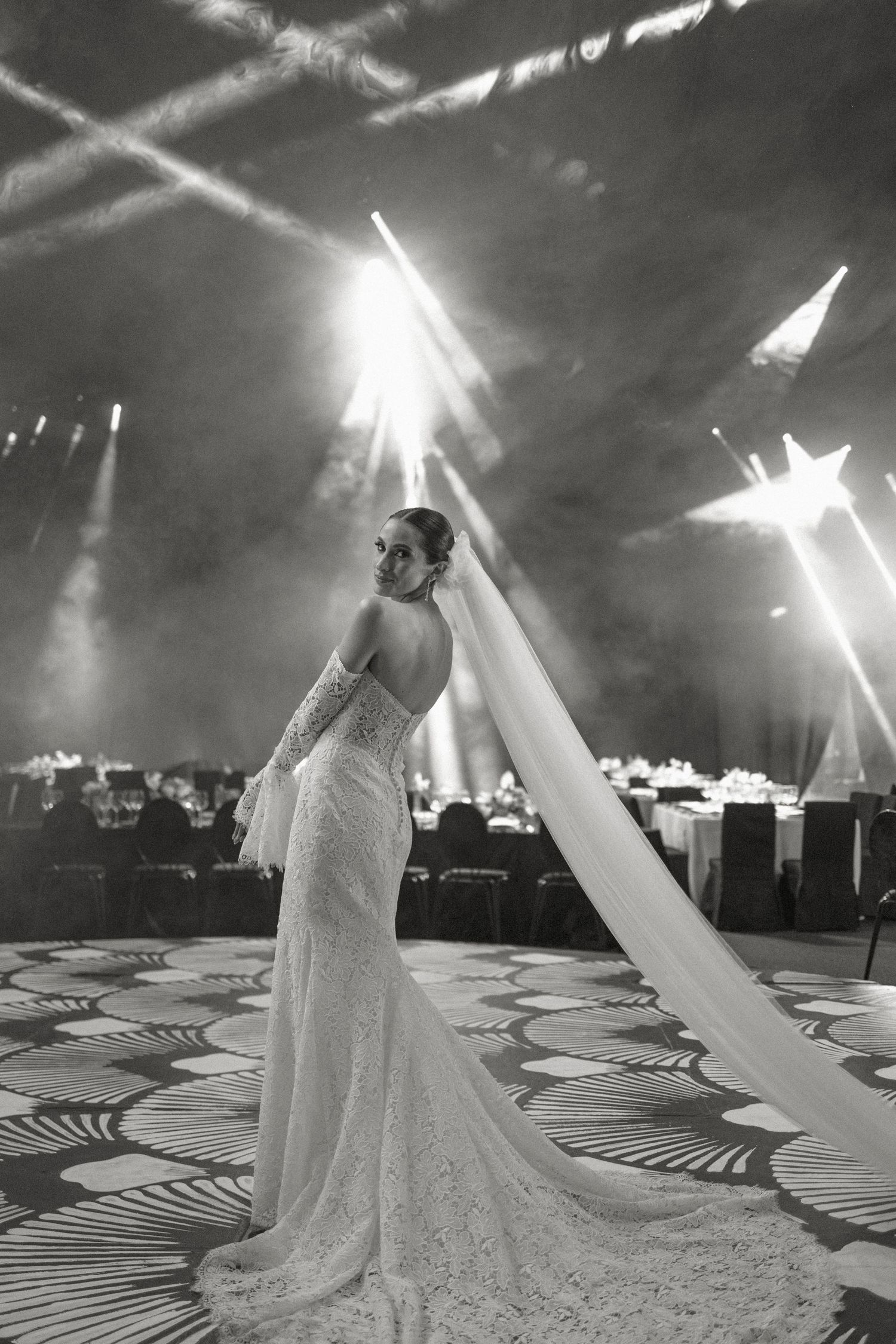 A black and white photo series showing a figure in a flowing white dress twirling under dramatic lighting on a patterned floor.