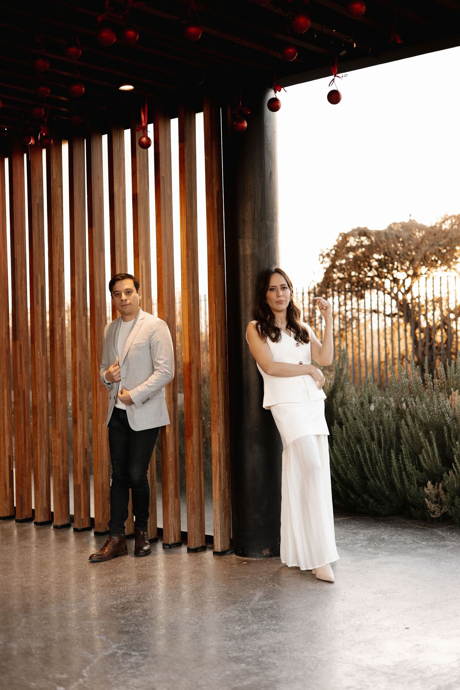 A couple dances together in a modern space with wooden slat walls and red lantern decorations above.