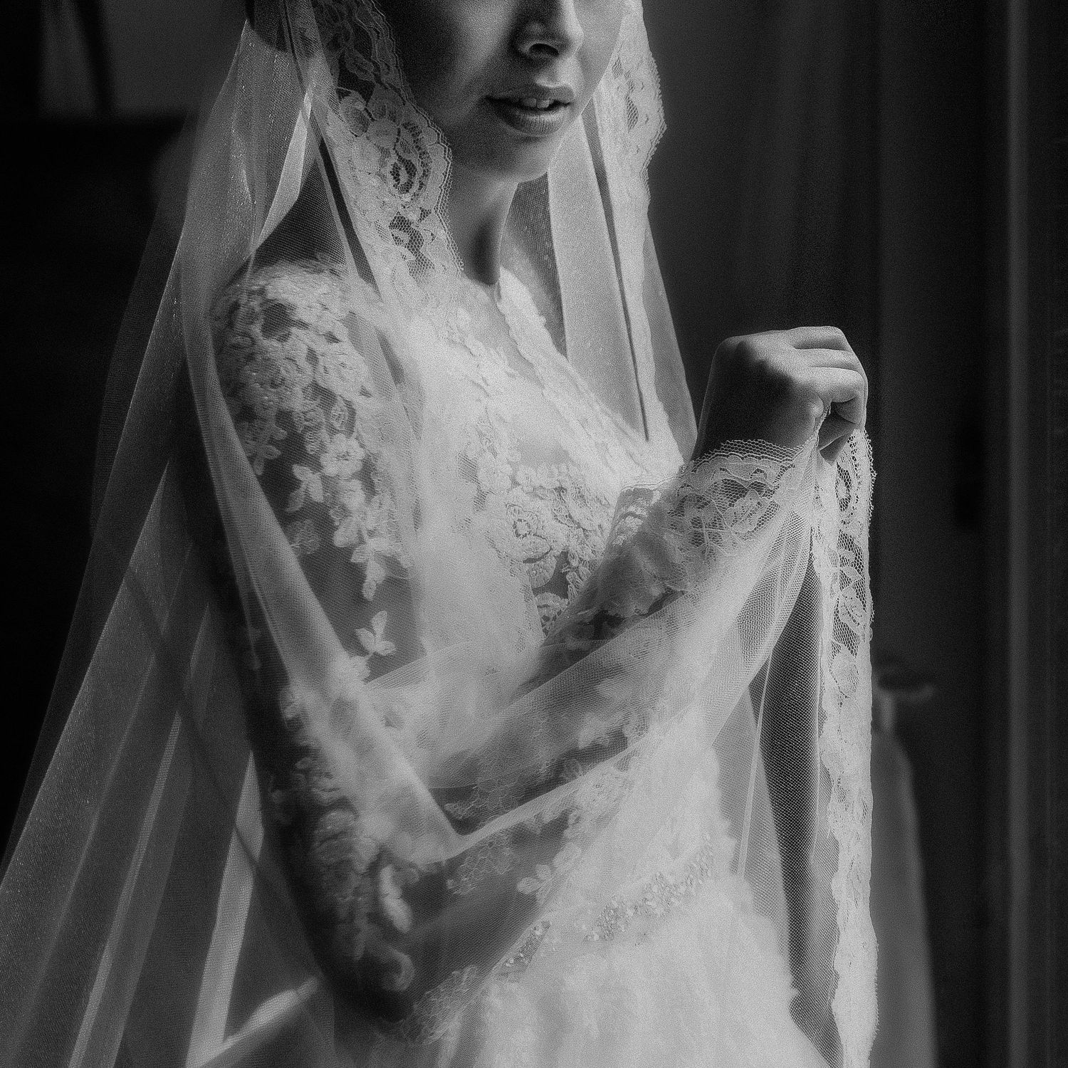 Black and white close-up photograph of intricate lace details on wedding attire.