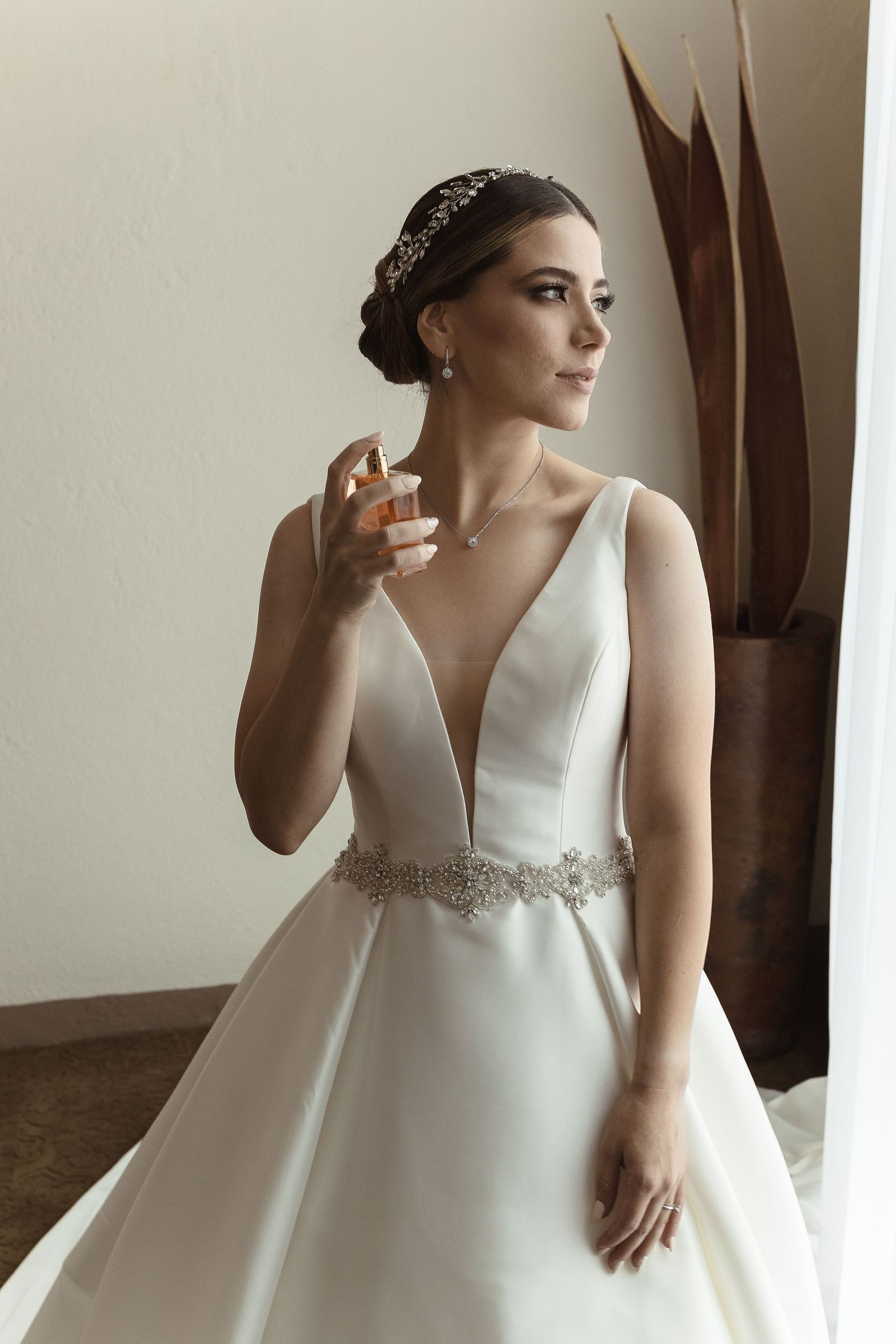 Elegant bridal portrait showing a white ball gown with beaded belt detail in soft window light.
