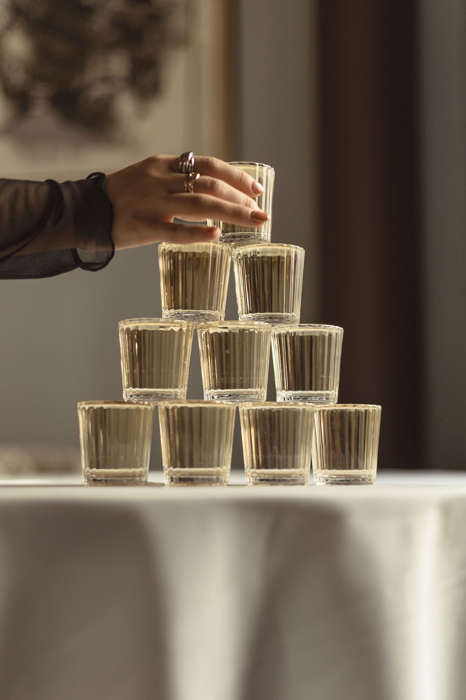 A sequence of images showing glass cups being arranged into a triangular formation on a white surface.