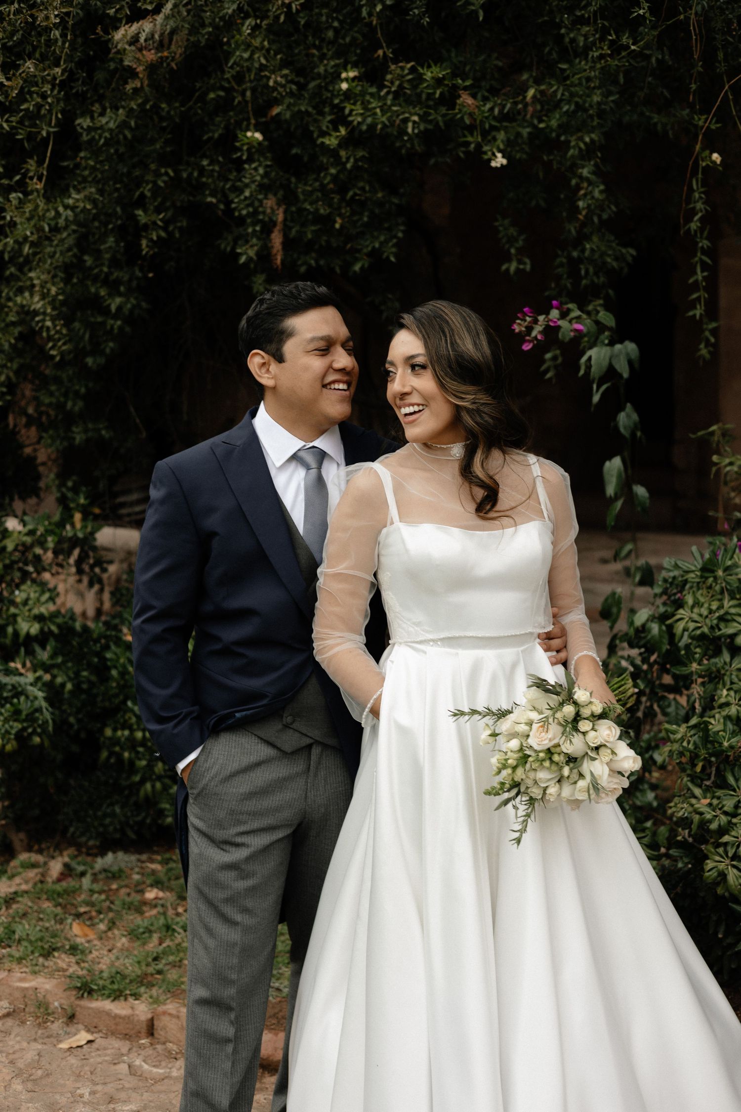 A couple shares joyful moments in a garden setting during their wedding celebration.