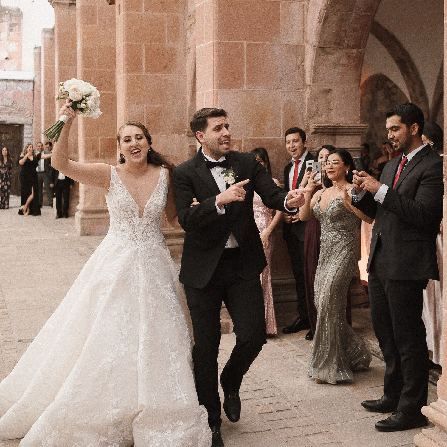 Wedding party celebrating in an ornate stone archway venue with classic architectural details.