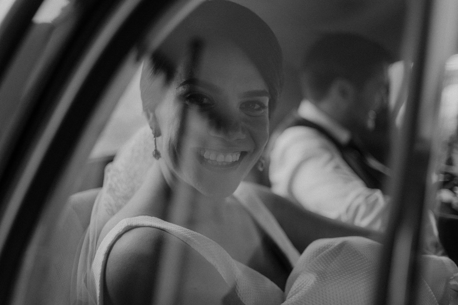 Black and white portrait through car window showing joyful moment.