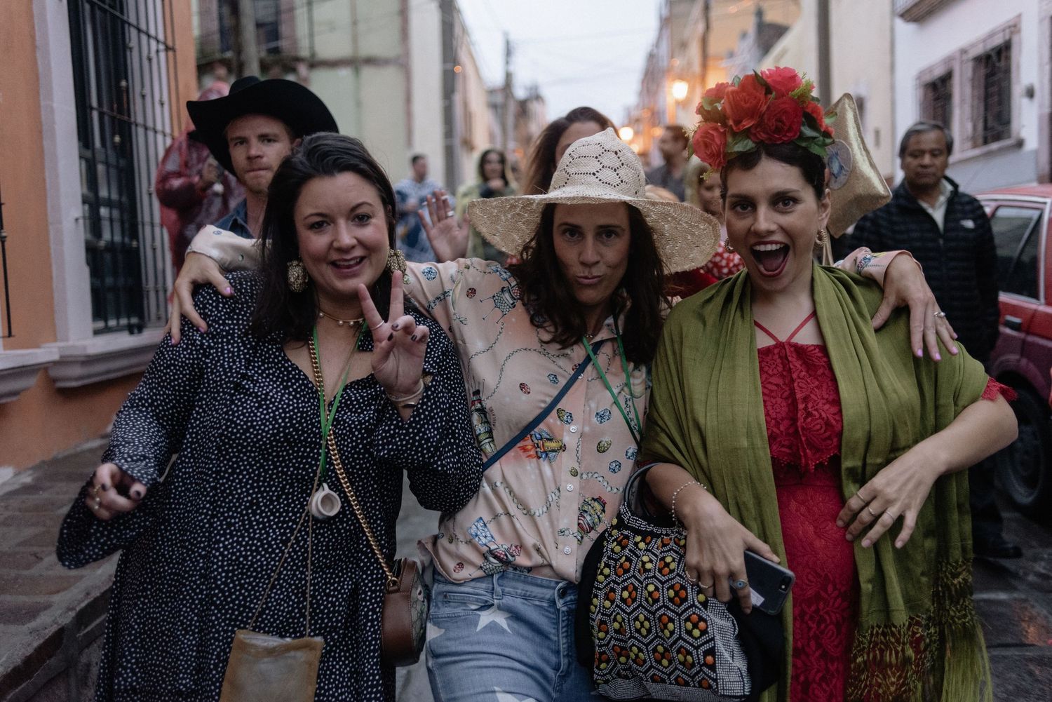 Three friends in vintage-inspired outfits walking together on a cobblestone street, sharing smiles and laughter.