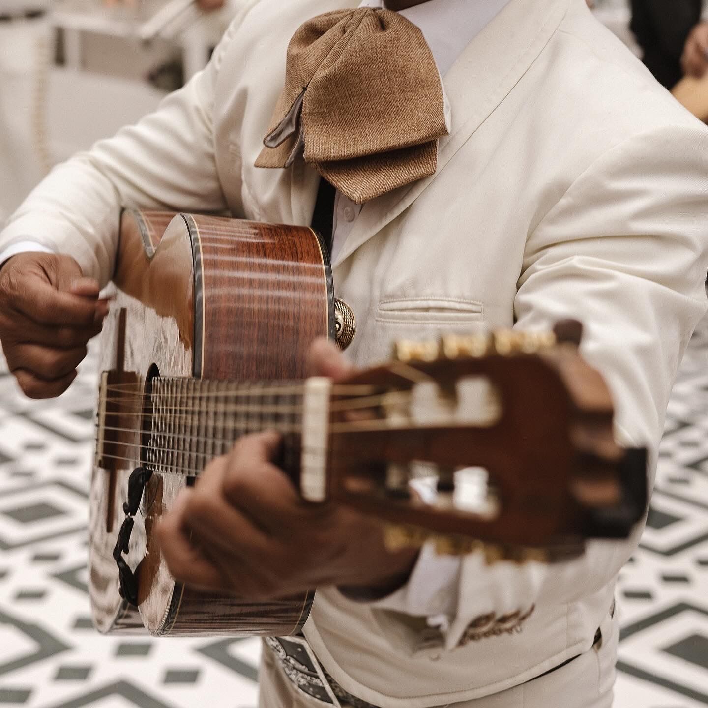 Musicians playing traditional acoustic instruments while wearing white formal attire.