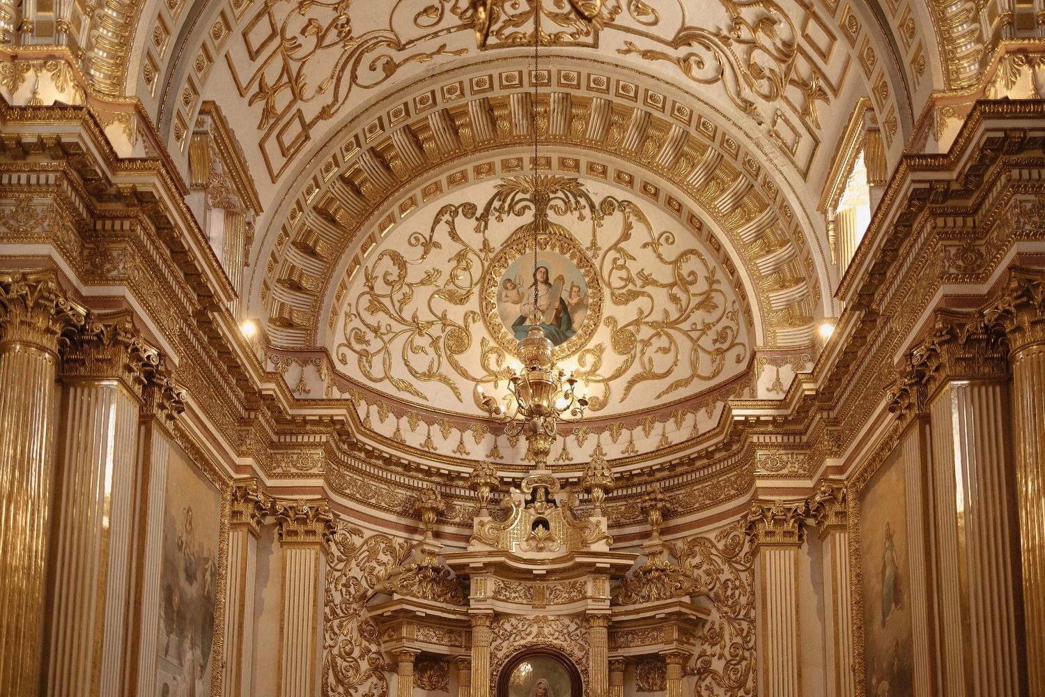 Ornate baroque cathedral interior with gilded details, vaulted ceilings, and intricate architectural decorations.