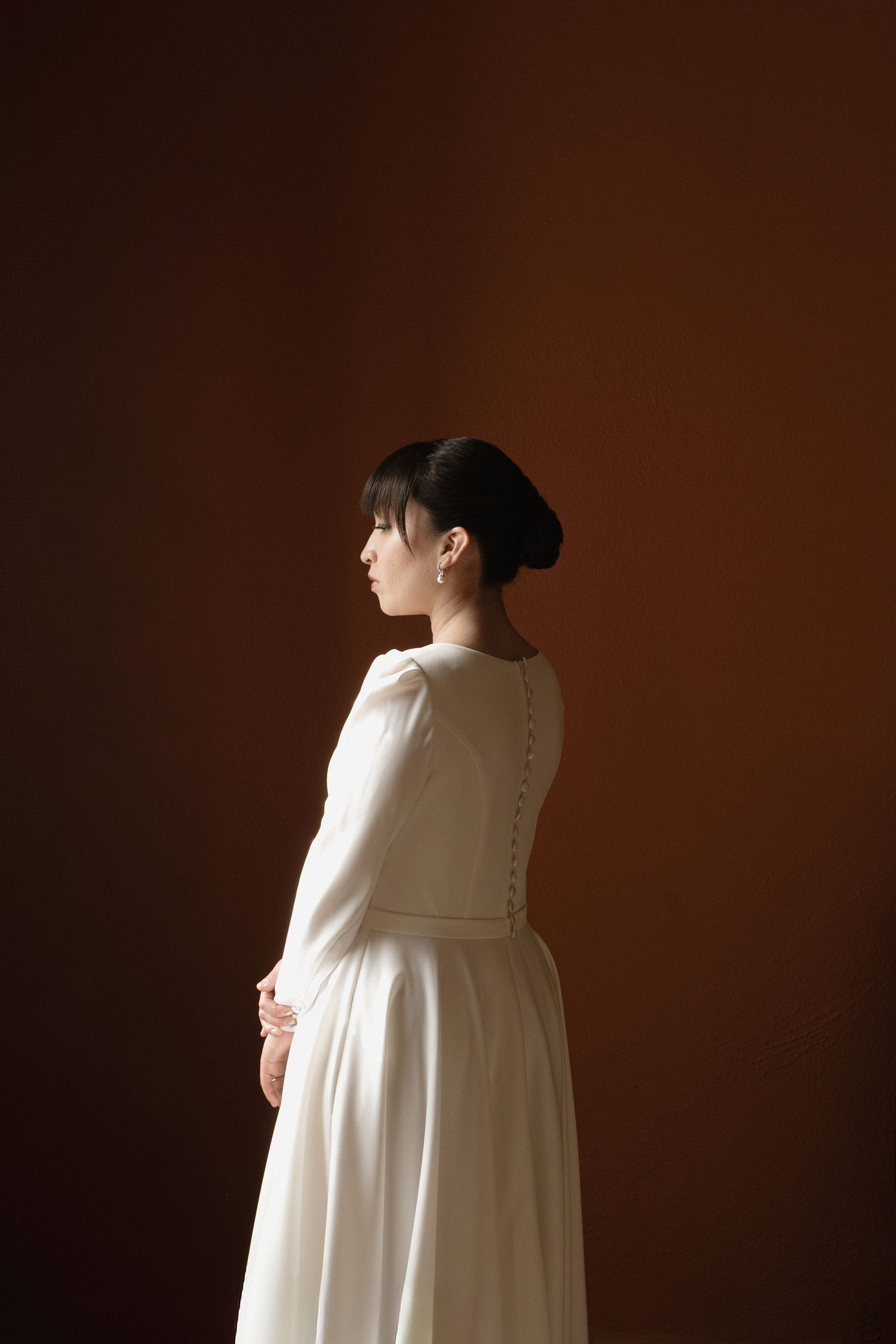 A series of photos showing a person in a flowing white dress against a dark brown background from different angles.