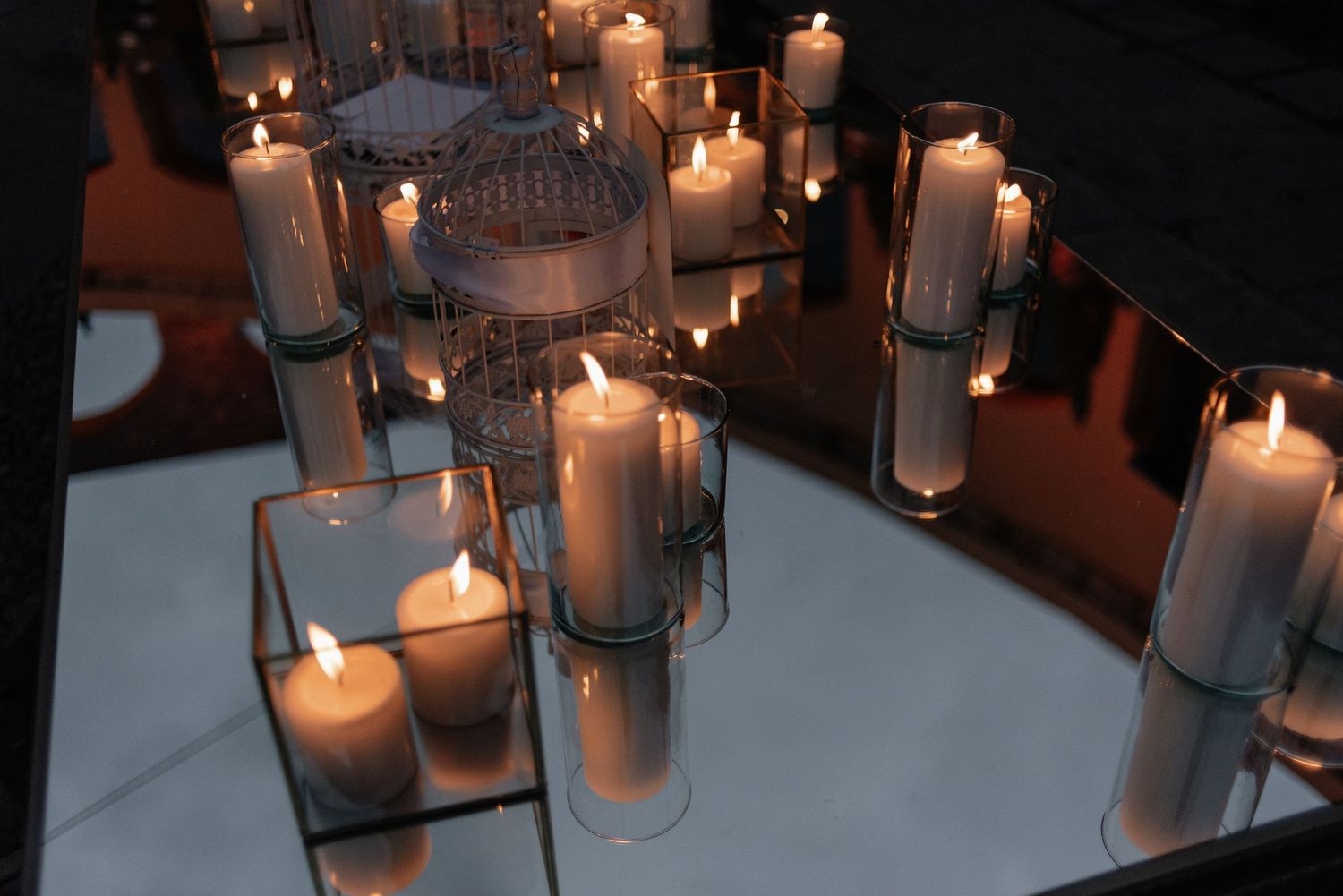 Multiple white pillar candles glowing in glass holders create a romantic and atmospheric lighting display.