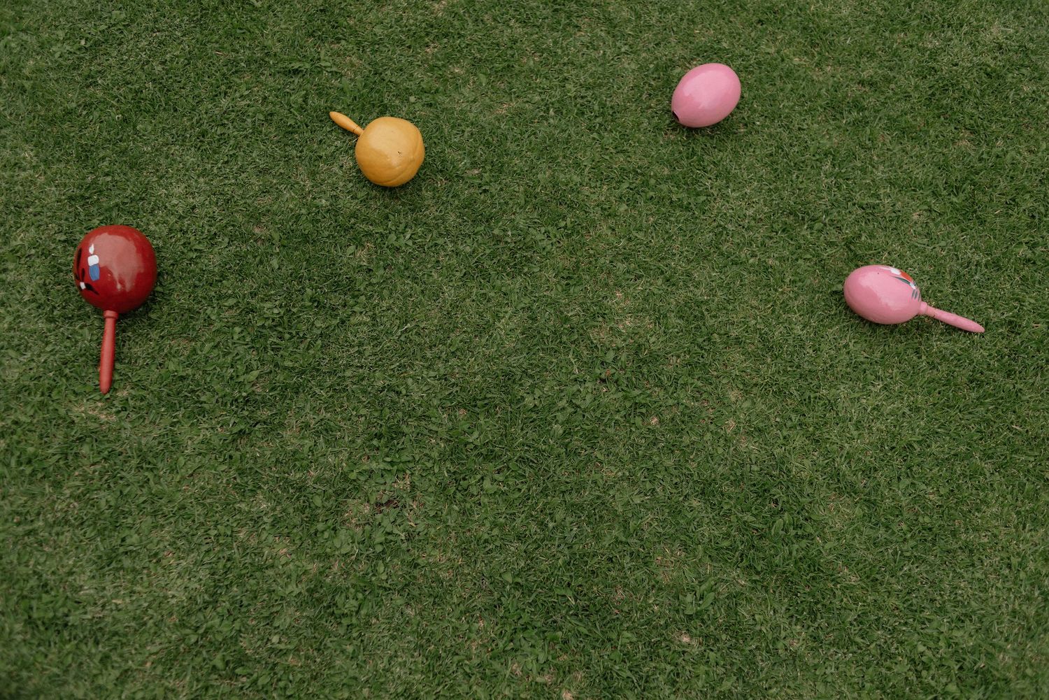 Colorful bocce balls scattered on a green grass lawn during a game.