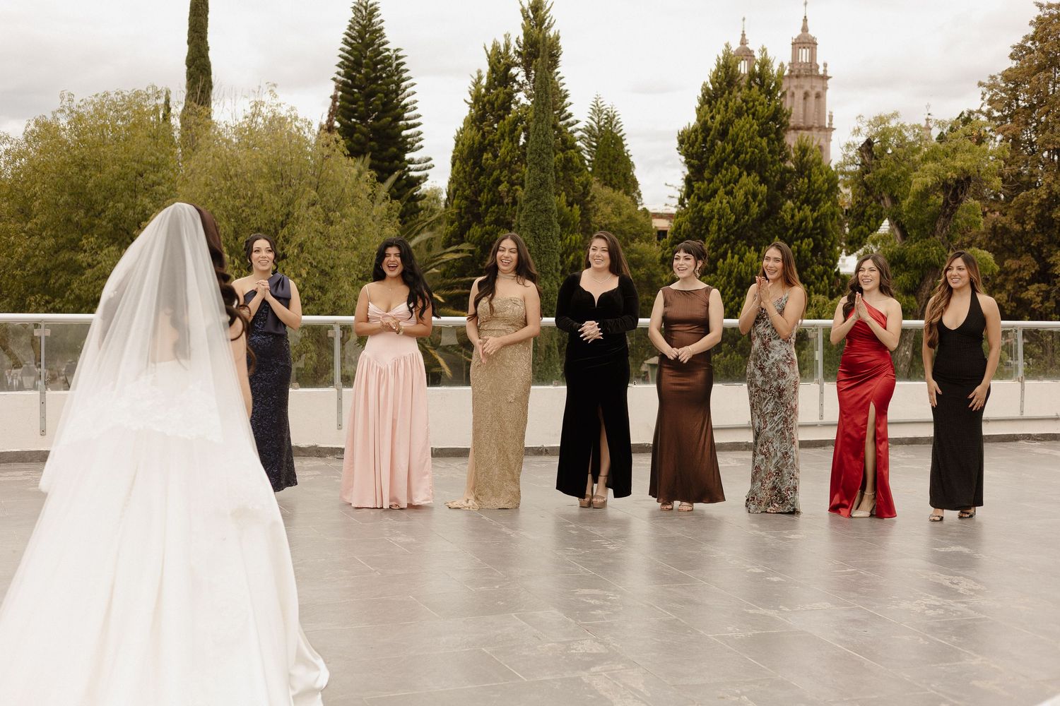 Wedding party members stand in a row outdoors against a natural backdrop during an autumn ceremony.