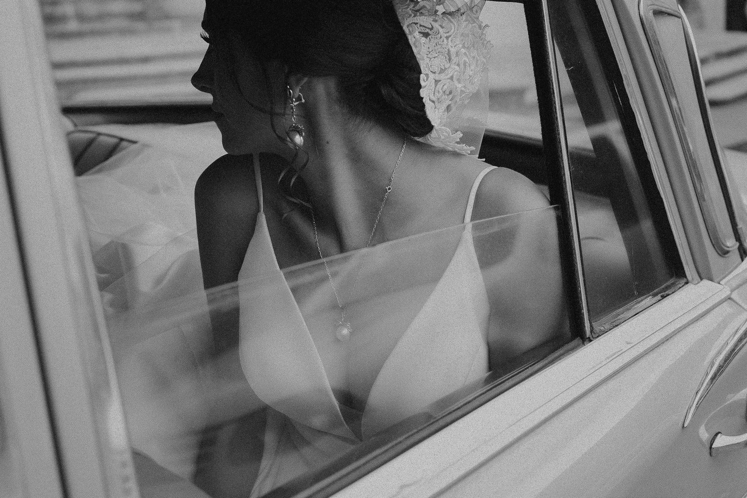 A black and white vintage photo shows a person in a car waving through the window.
