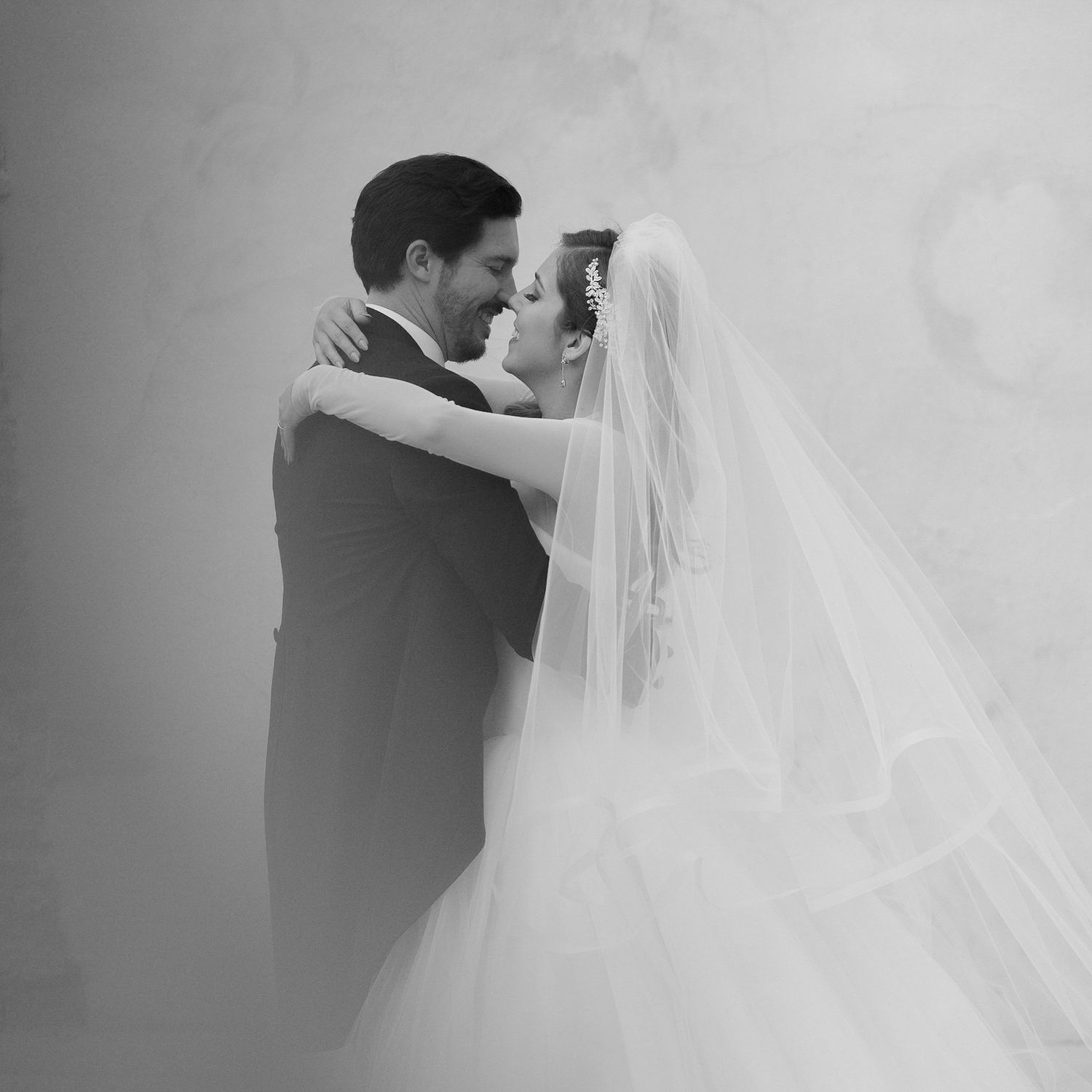 A romantic black and white wedding moment captured with flowing veil and formal attire.