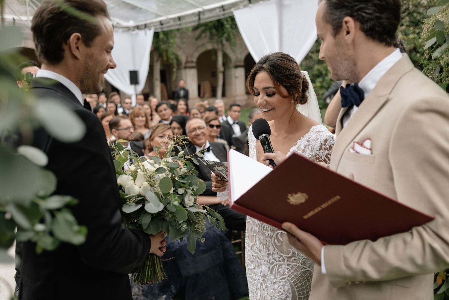 Beautiful wedding ceremony taking place outdoors with couple exchanging vows in front of officiant and guests.