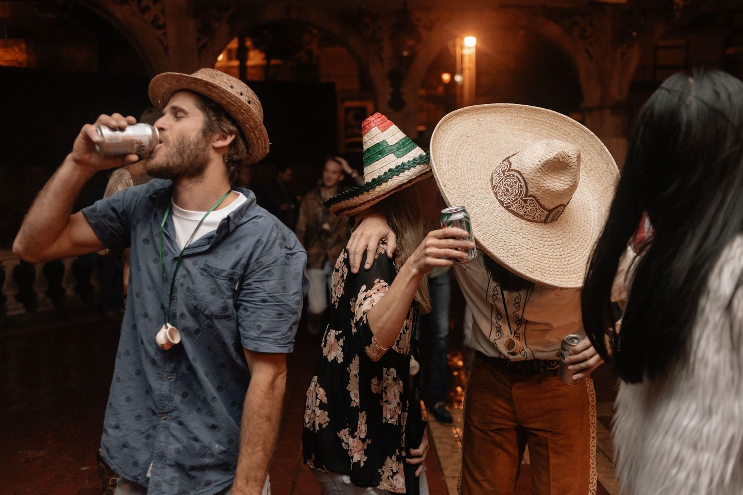 Group of young people enjoying drinks at a nighttime party with cowboy hats and festive attire.
