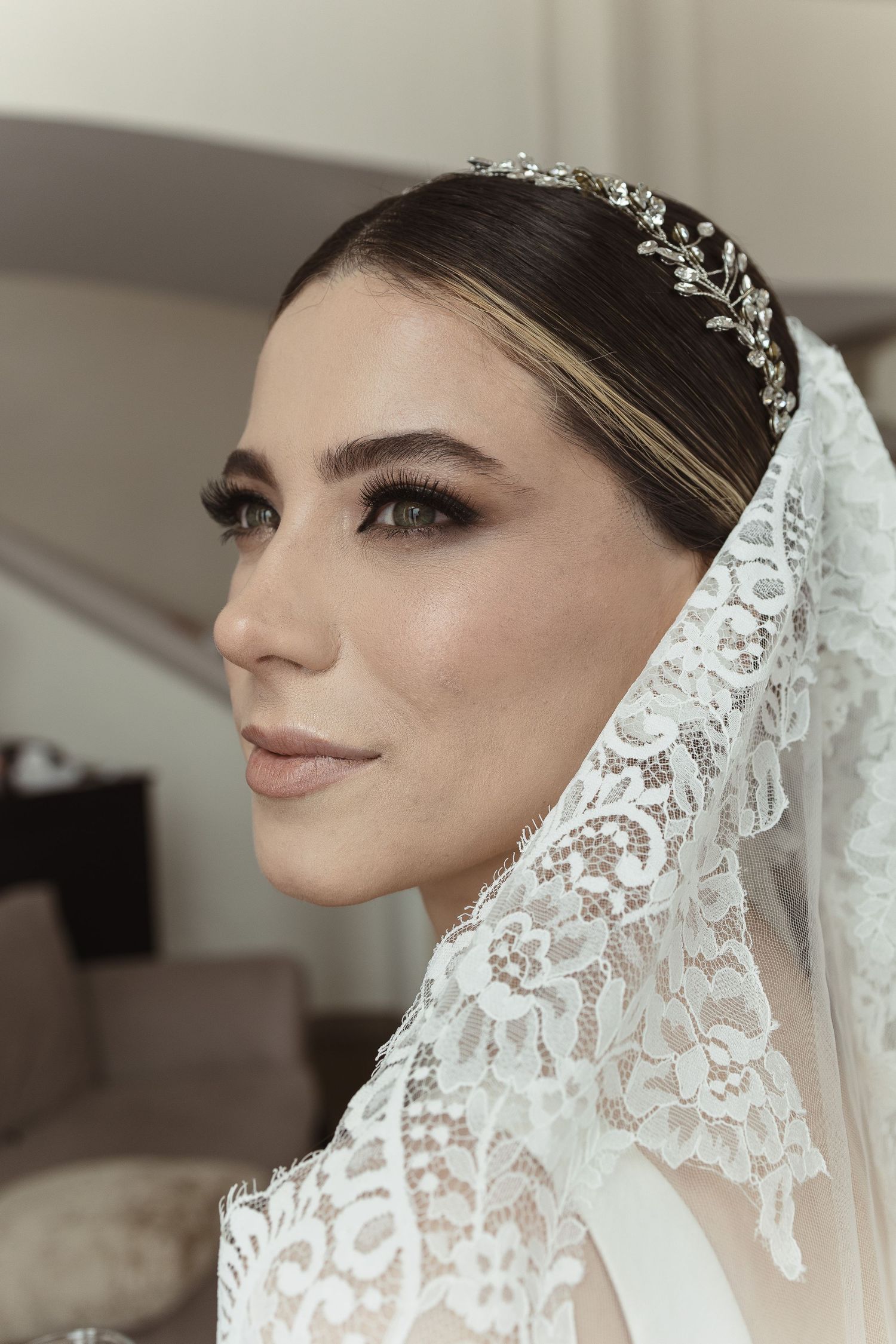 Close up details of delicate white lace veil and bridal accessories against neutral background.