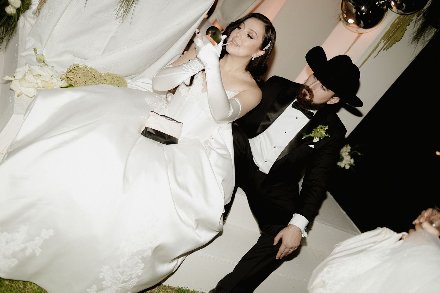 A couple in formal wedding attire performs karaoke together at their reception celebration.