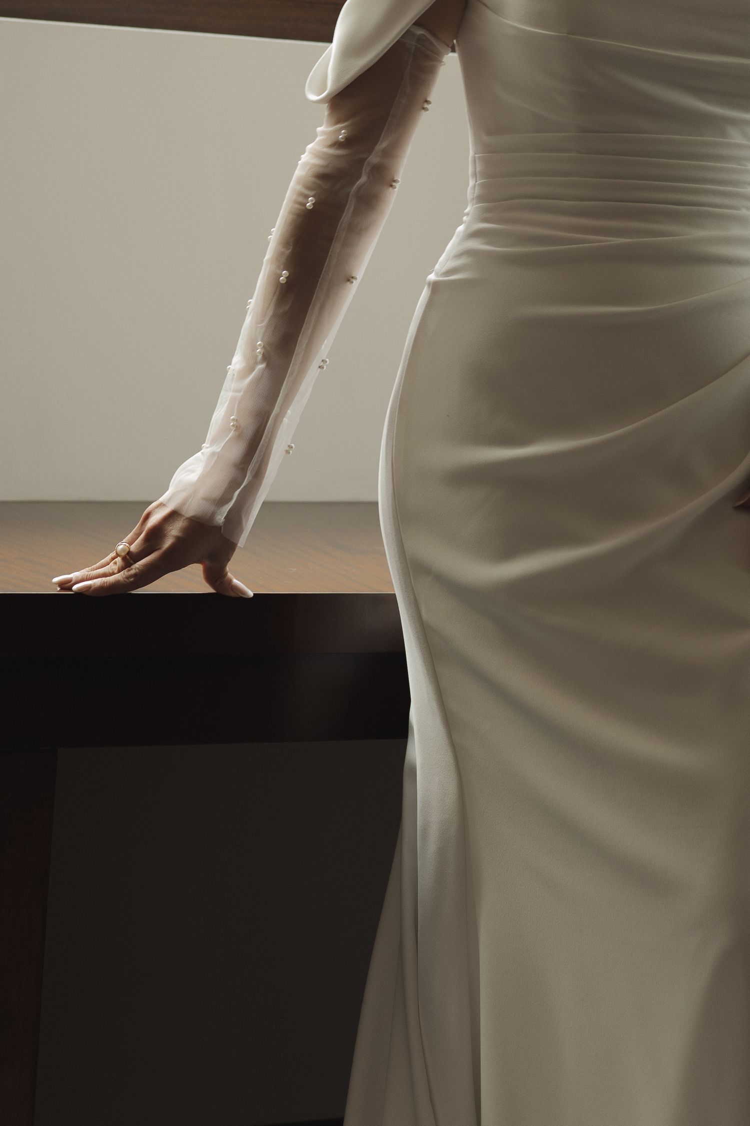 Close-up view of a sleek white wedding dress showing elegant fabric draping and silhouette details.