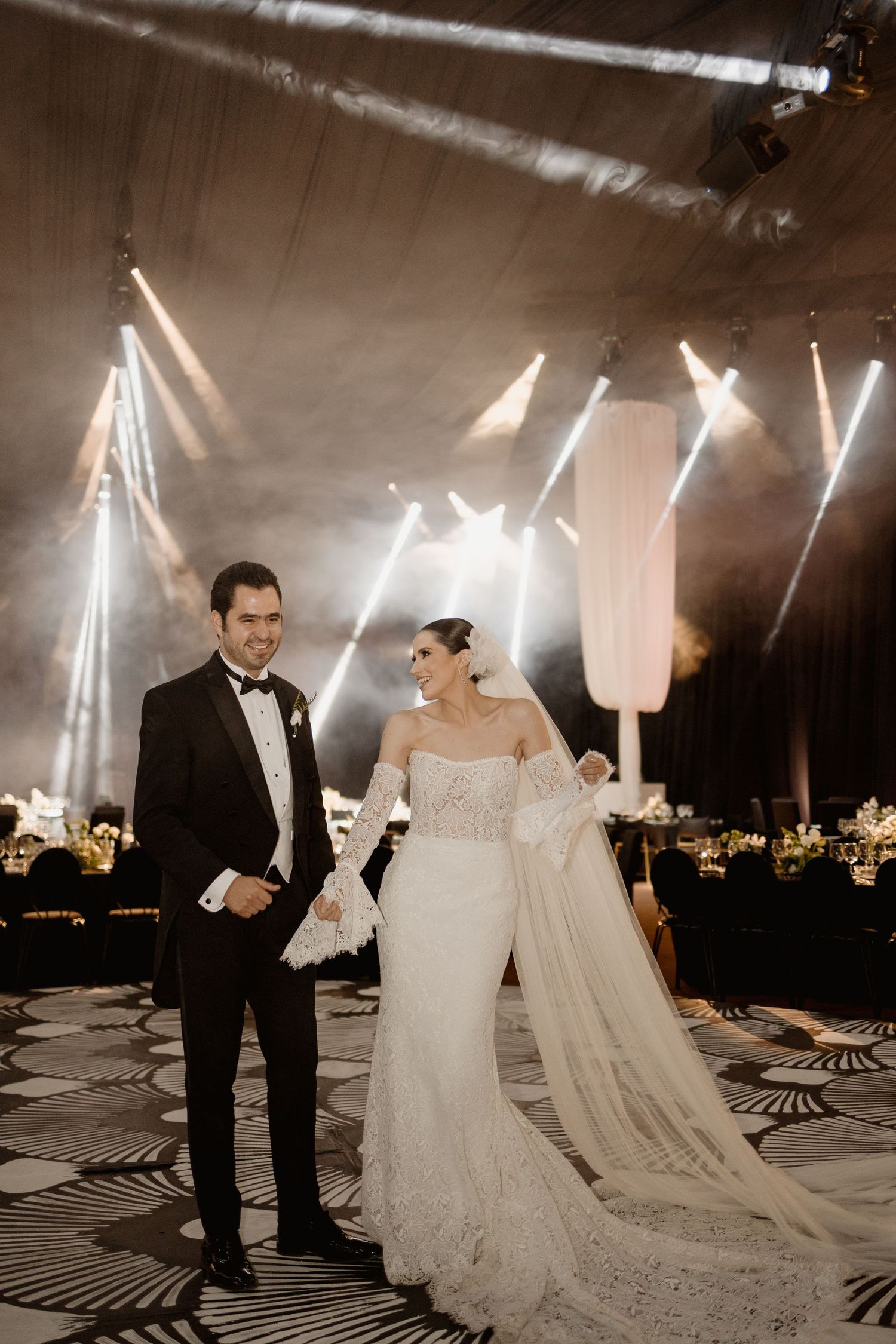 A couple shares a romantic dance moment under dramatic lighting at their wedding reception.