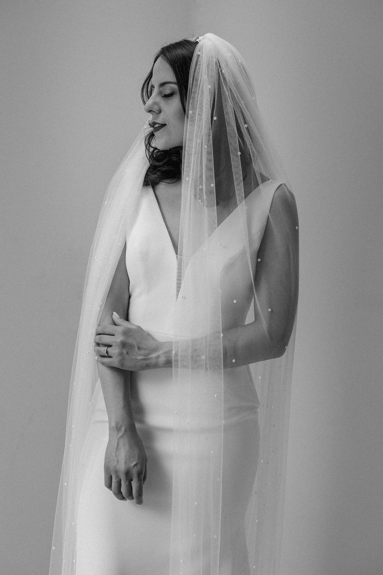 Black and white portrait of a bride in a modern wedding dress with delicate veil details.