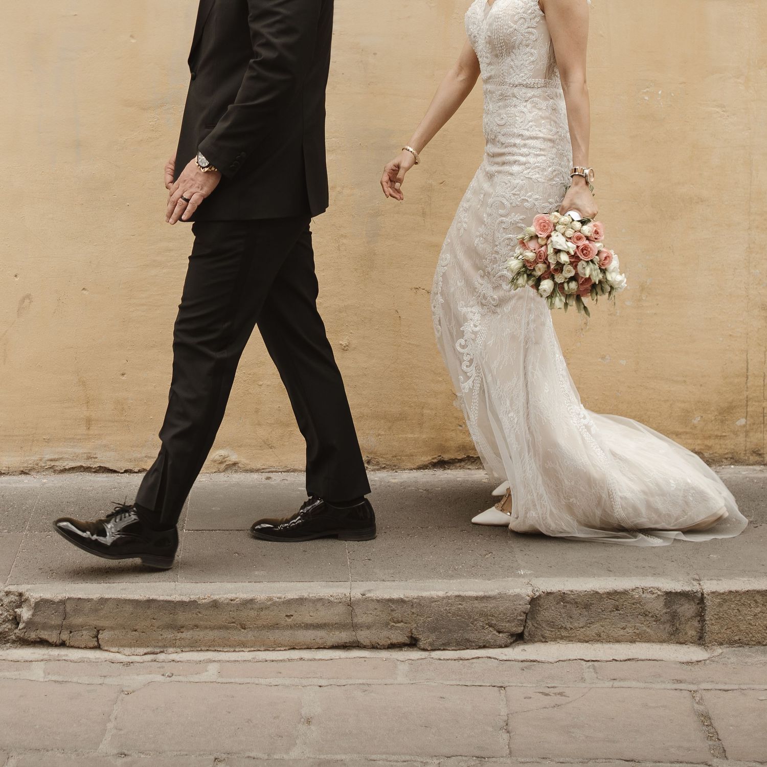 Wedding couple walking together, showing dress train and formal shoes.