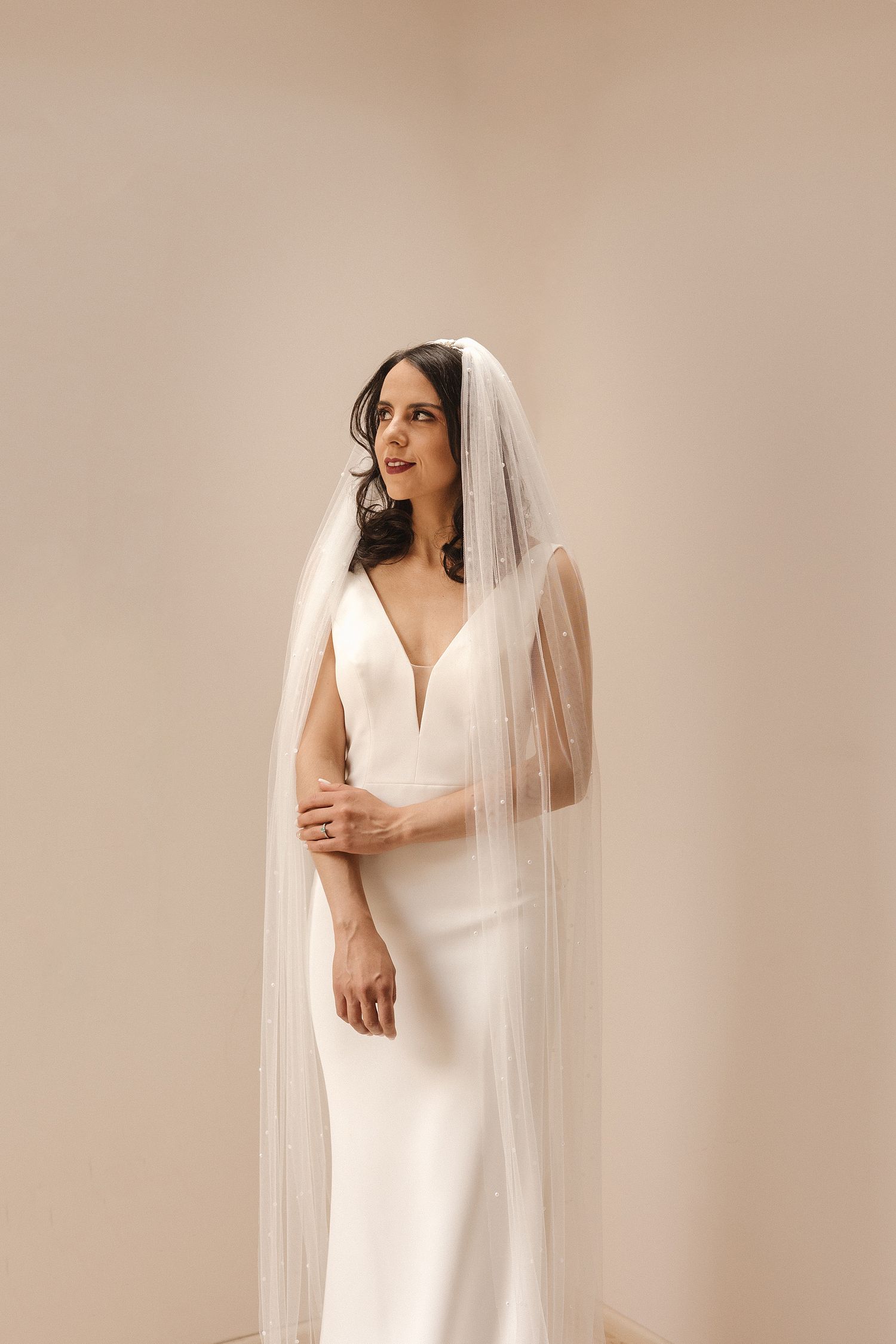 A series of elegant bridal portraits showing a white wedding dress and flowing veil against a neutral backdrop.