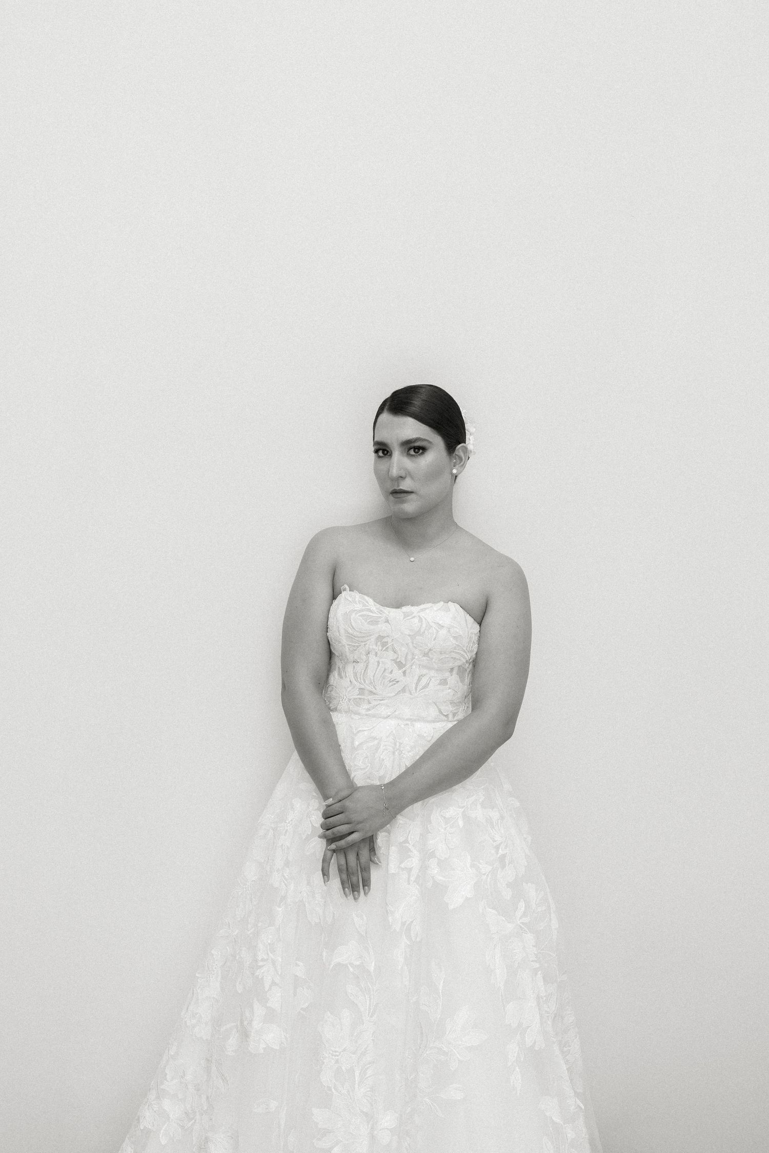 A series of four black and white photos showing a person in a strapless white wedding dress against a light background.