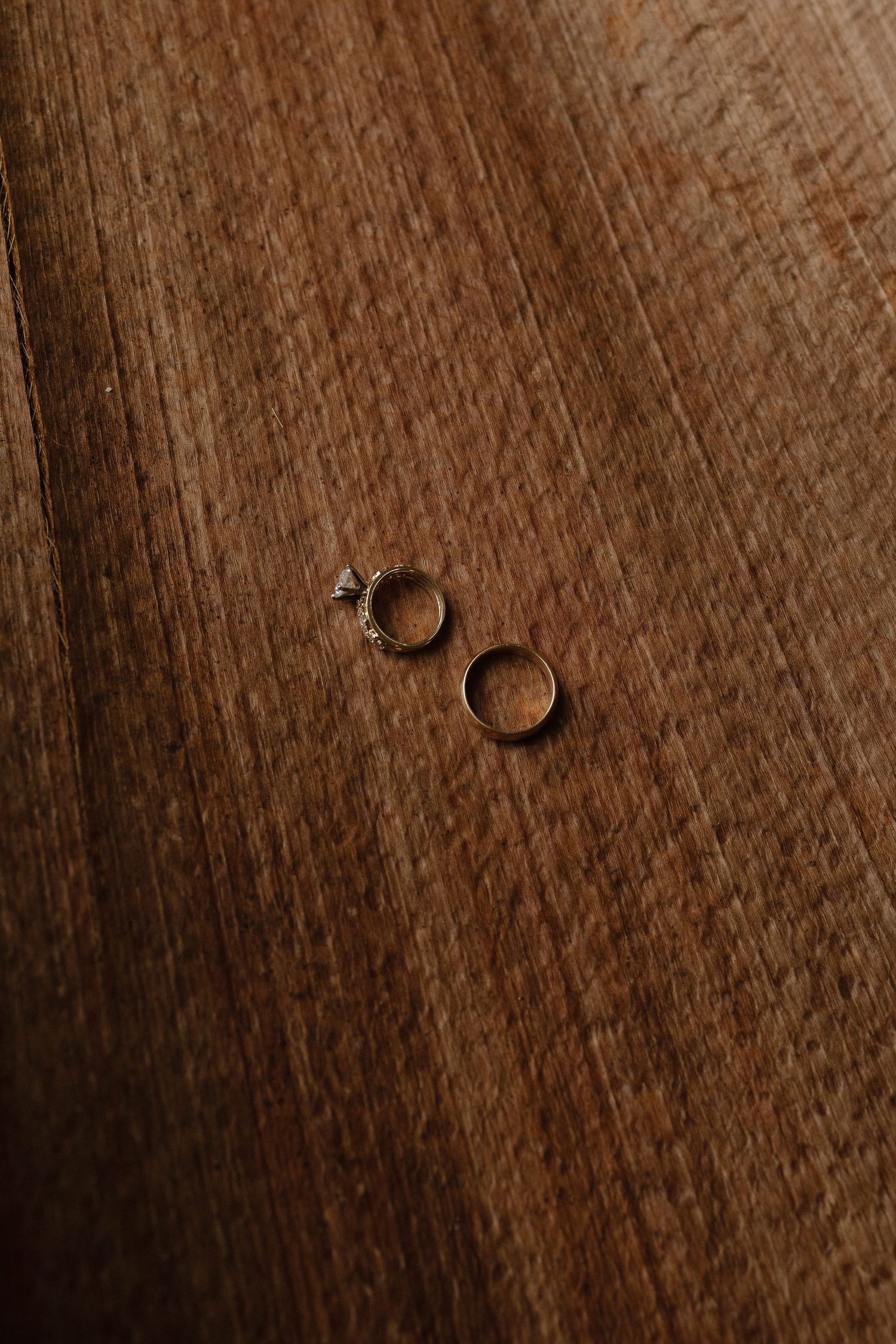 Close-up of a wedding ring casting a shadow on weathered wooden surface with rich texture and grain.