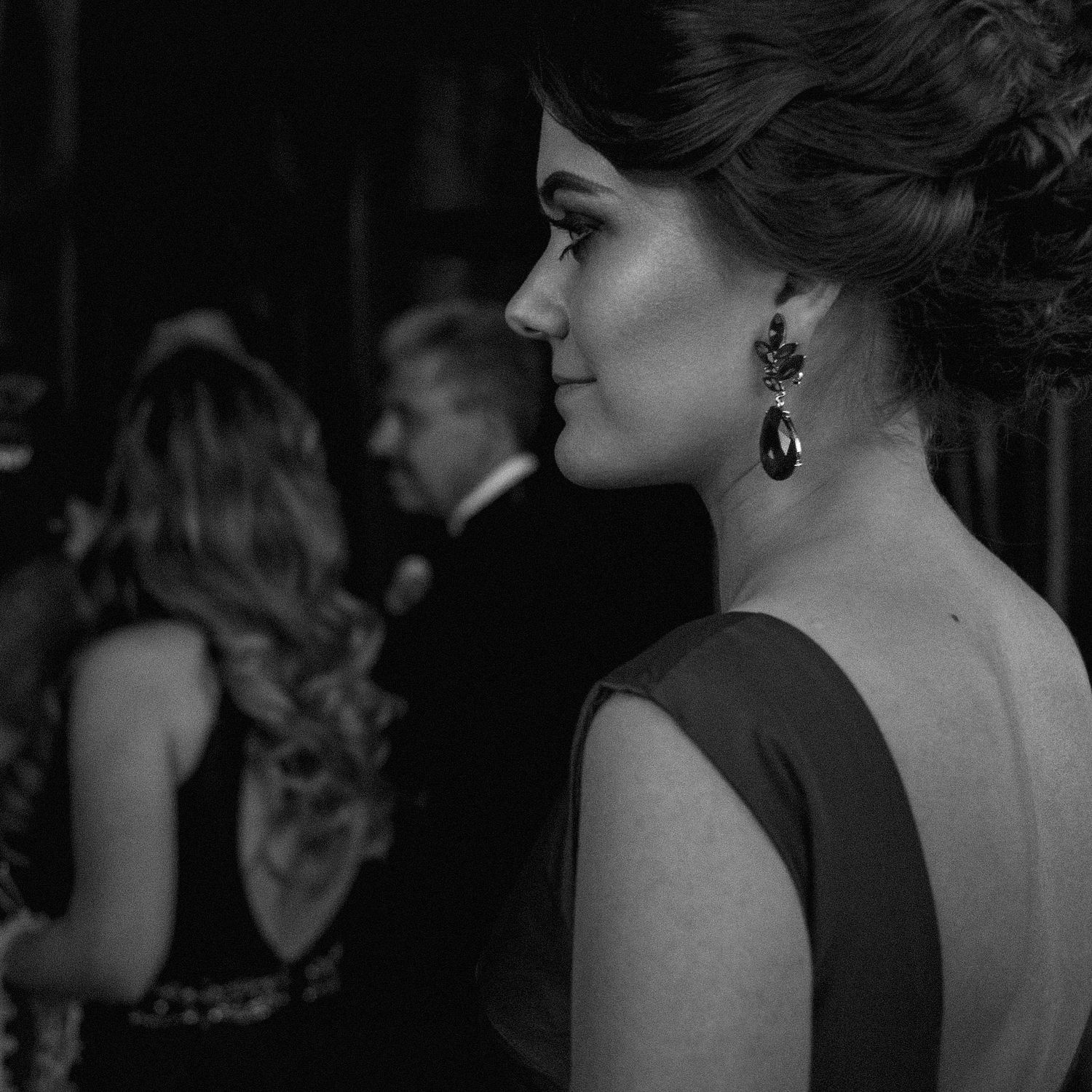 Elegant black and white portrait showing dramatic side profile and statement earrings.