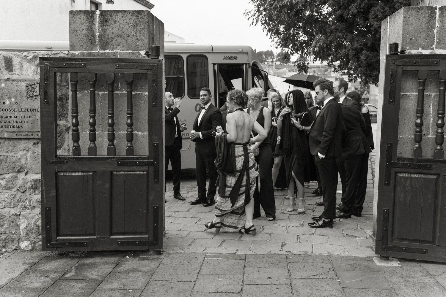 A crowd of people gathered at an entrance gate in a vintage black and white photograph.