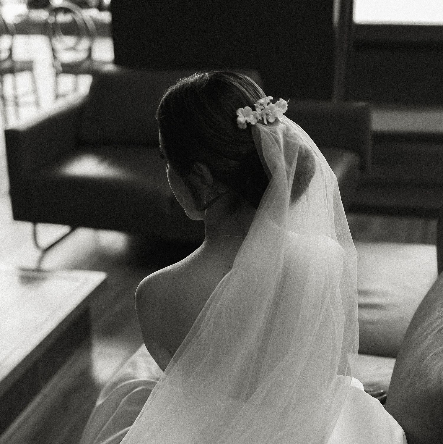 Black and white wedding photo showing a bride in a flowing veil and dress from behind.