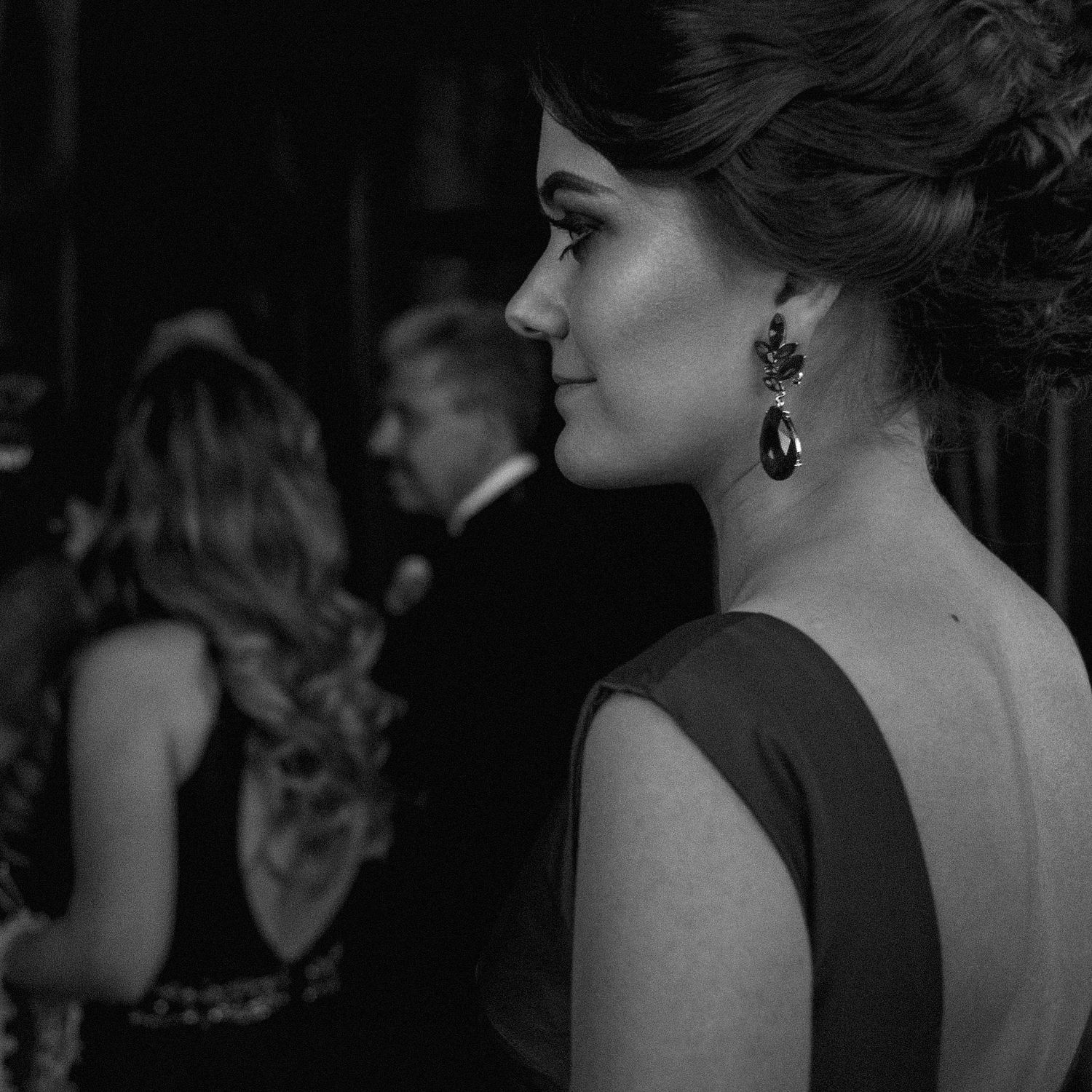 Elegant formal event with guests in evening attire mingling in a dimly lit venue.