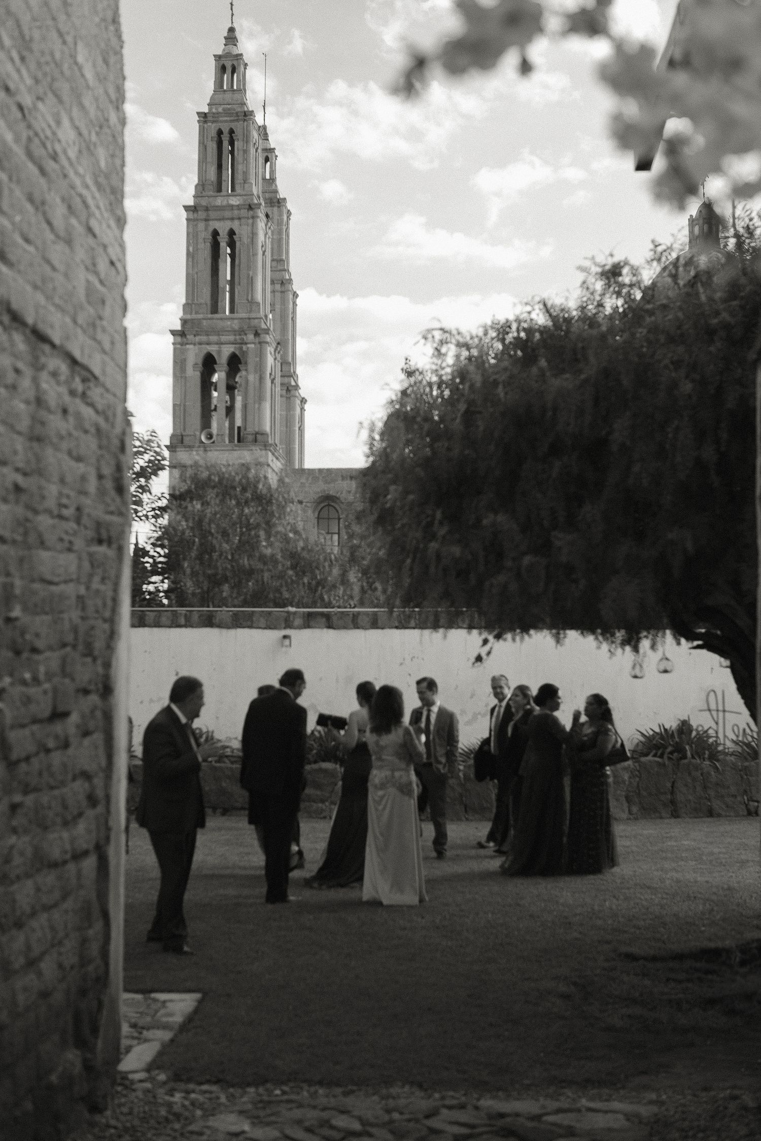 Black and white photo of wedding party silhouettes against a church tower backdrop.