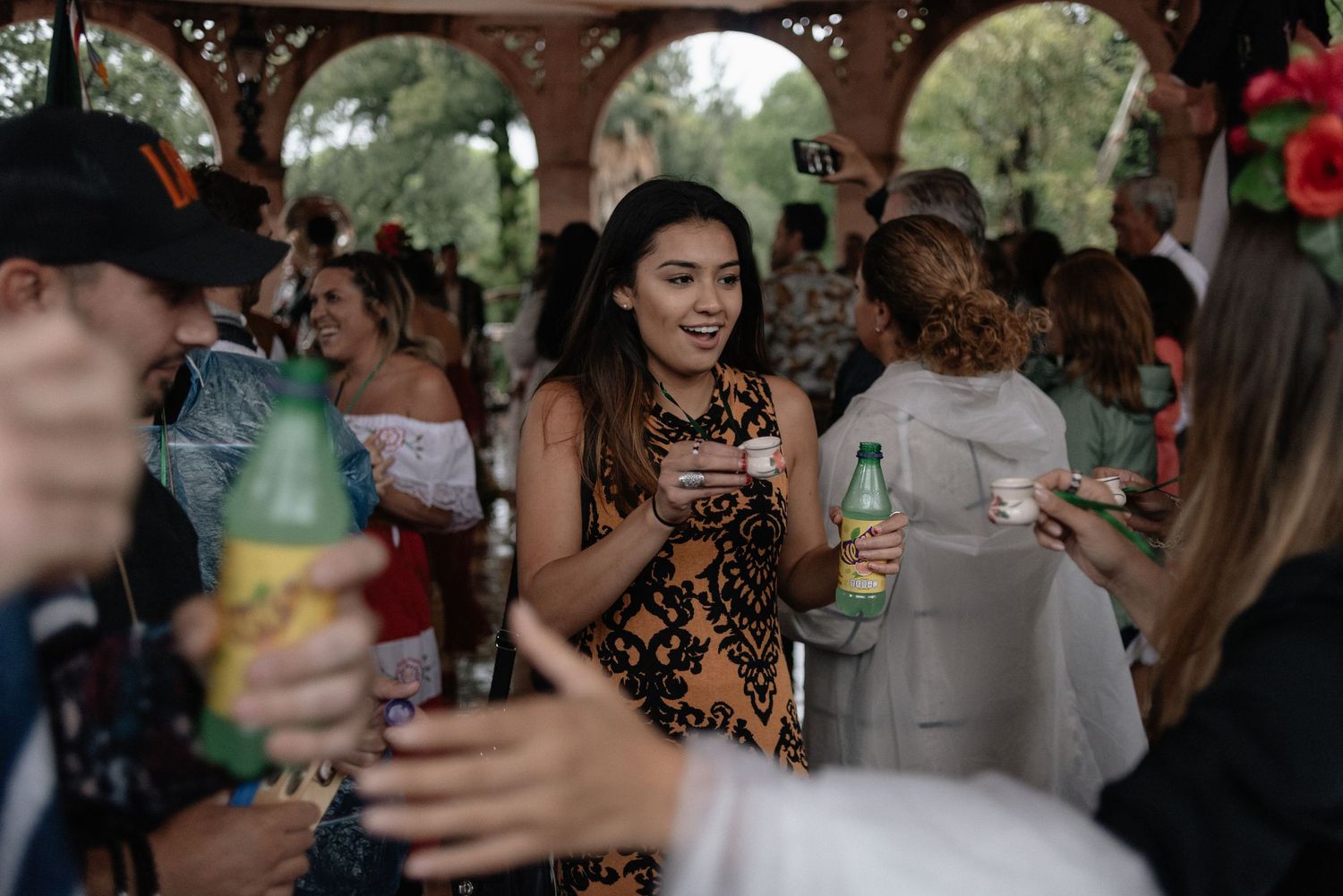 Group of people enjoying drinks together at a covered outdoor venue with ornate archways.