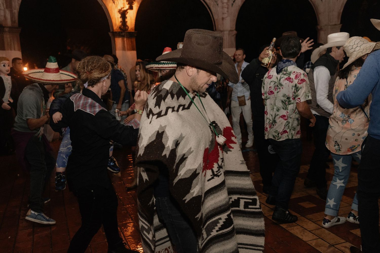 A crowded dance floor with people wearing winter sweaters and casual clothing at a dimly lit indoor venue.