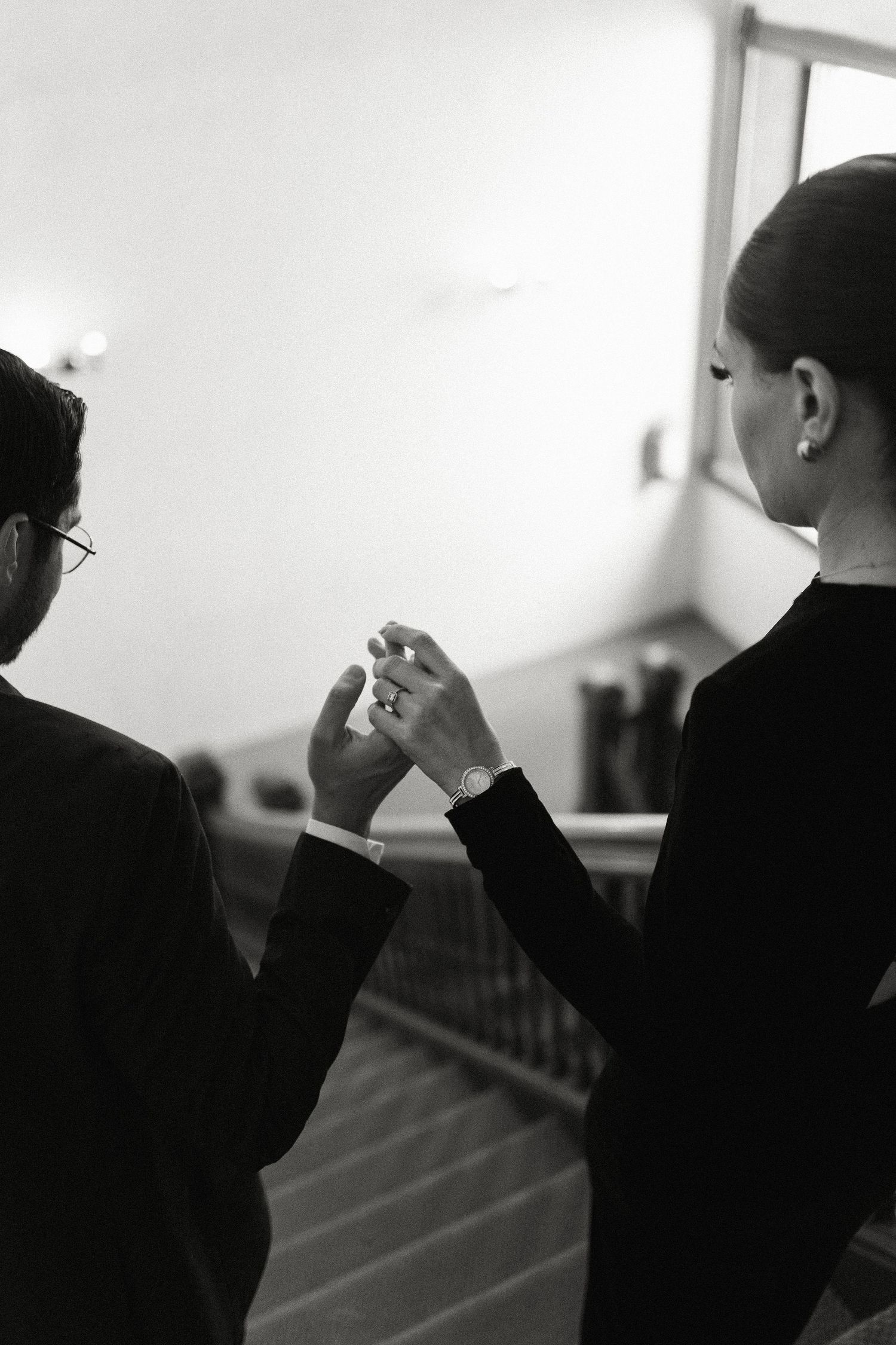 Two people in black attire share an intimate moment in a monochrome photograph.