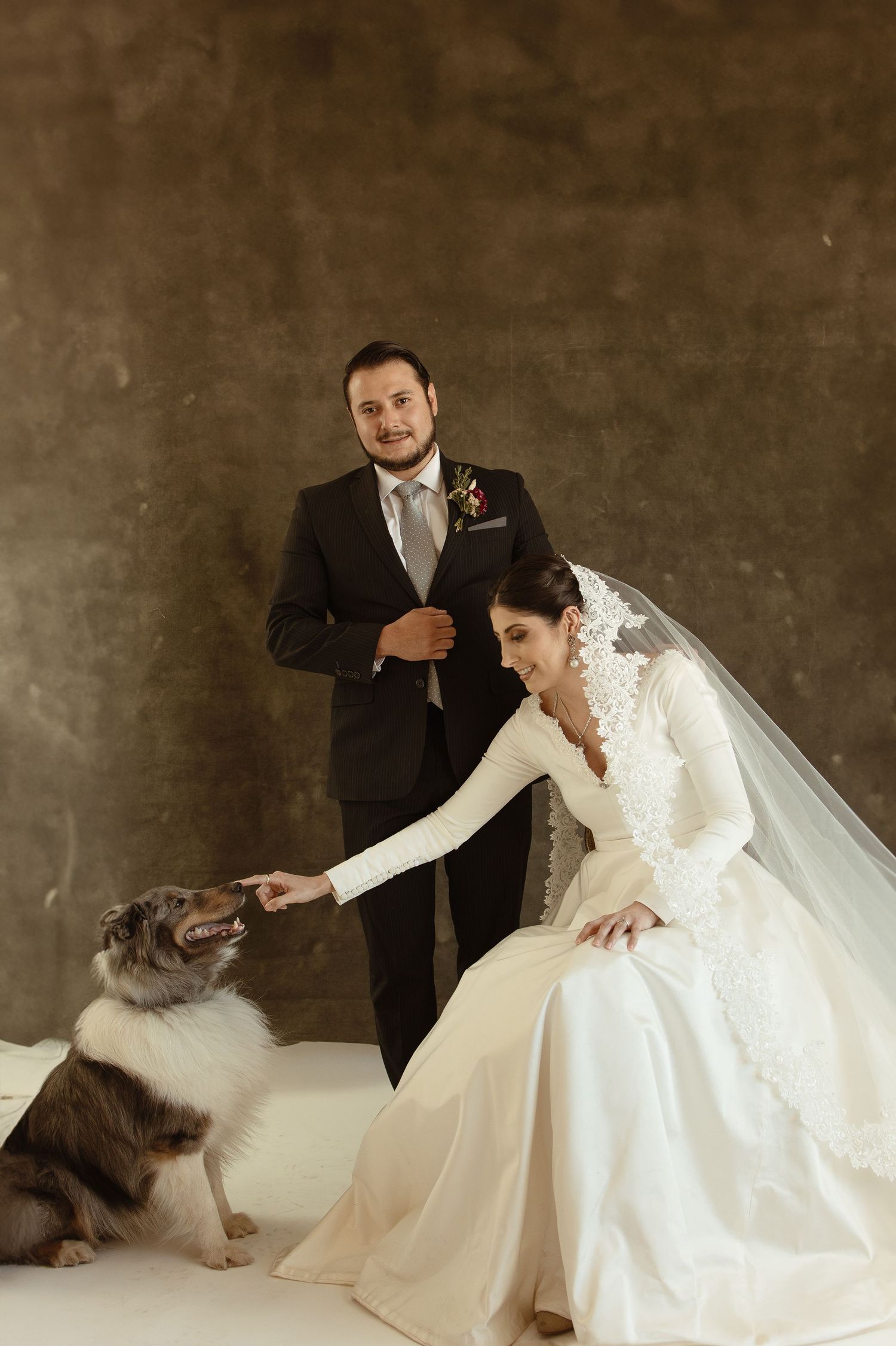 A bride in a flowing white gown plays with a fluffy grey cat in a series of candid wedding photos.