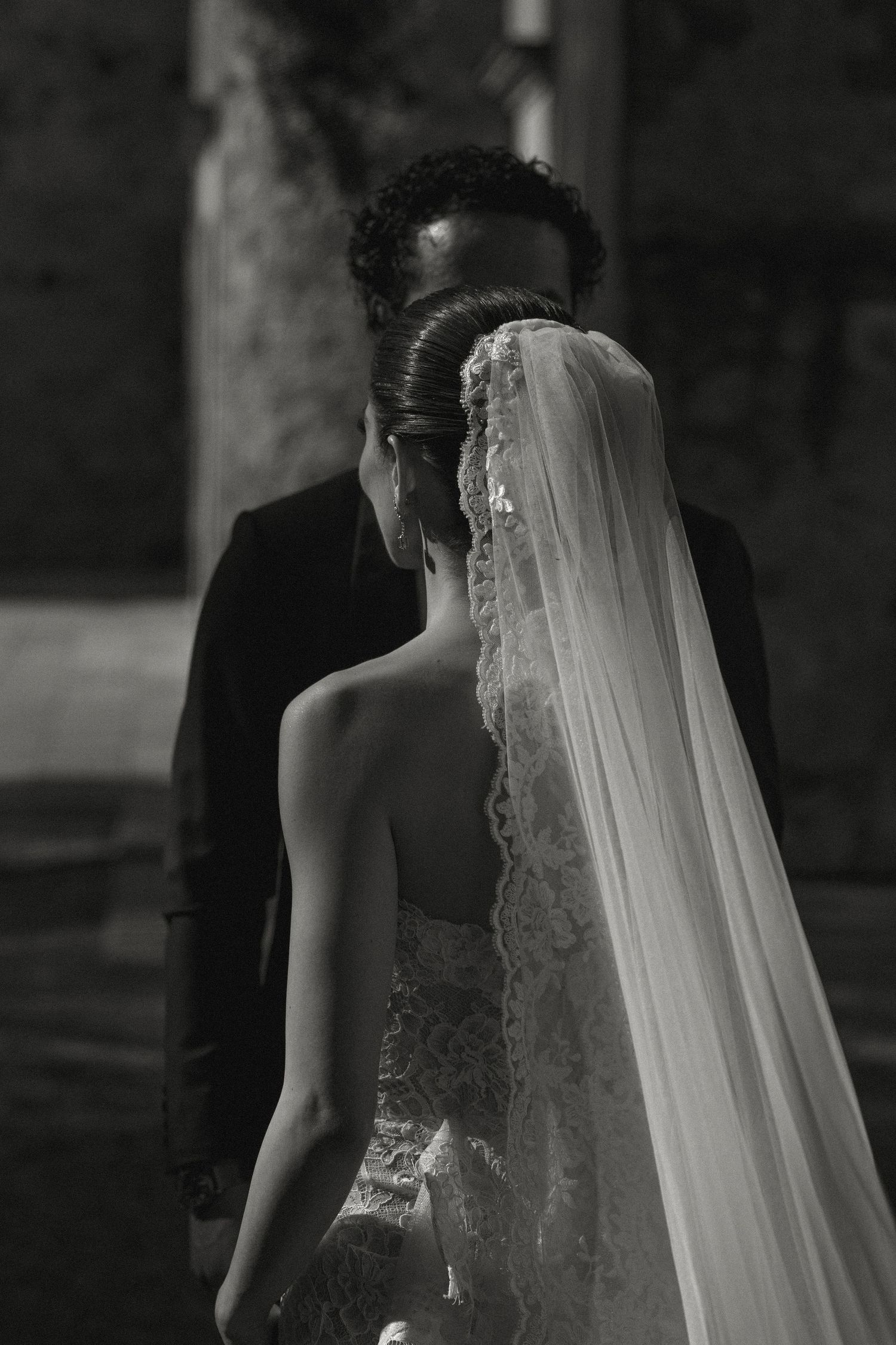 A series of black and white wedding photos showing a bride in a lace dress with flowing veil from different angles.