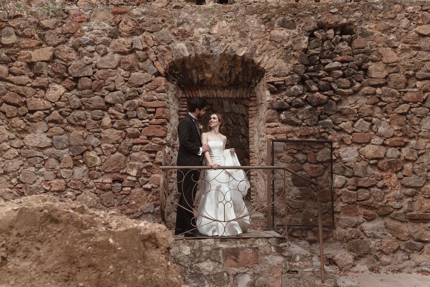 Wedding portraits captured against weathered stone walls and archways.
